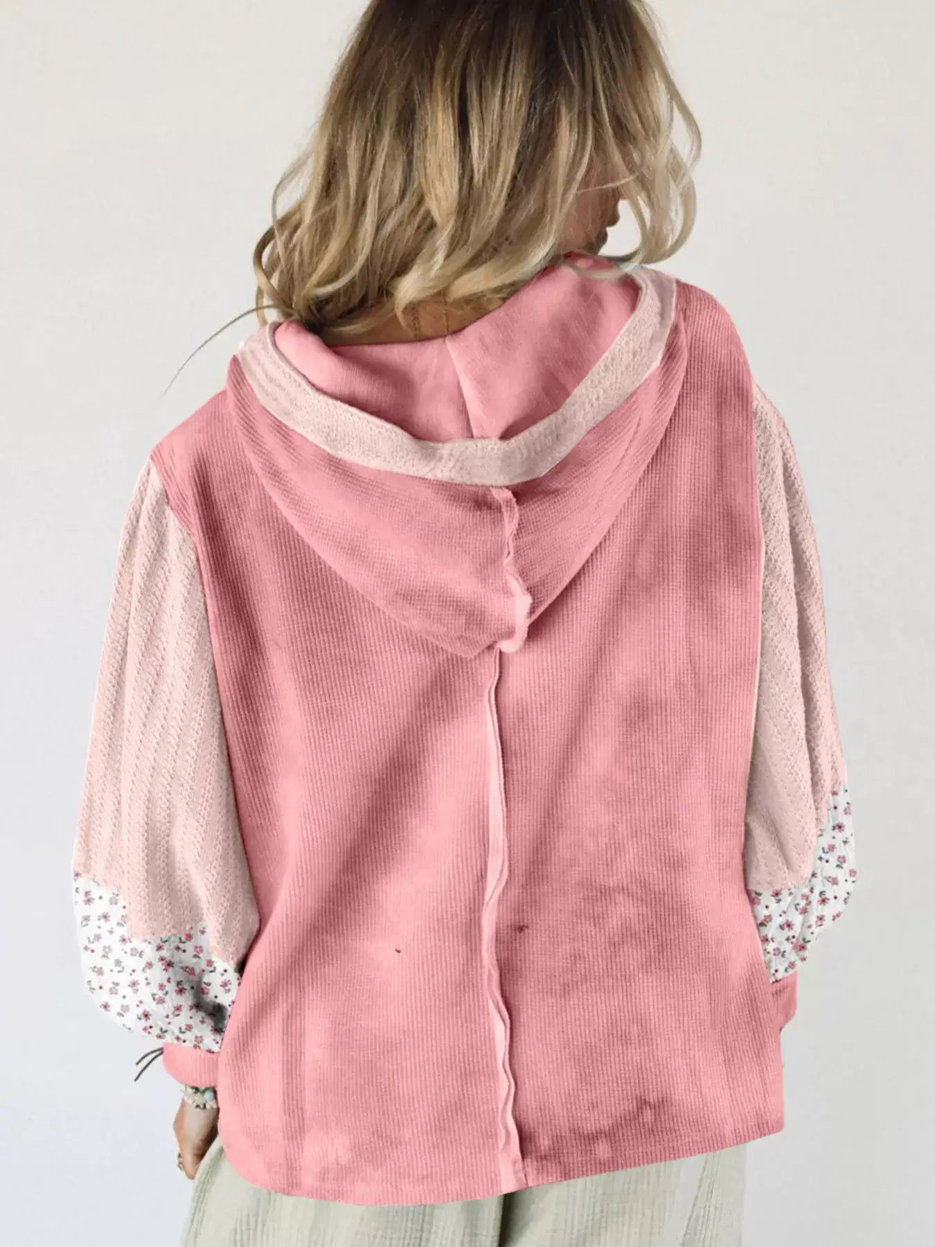 Back view of a woman wearing a Floral Patch V-Neck Sweatshirt in soft pink with floral details on sleeves.