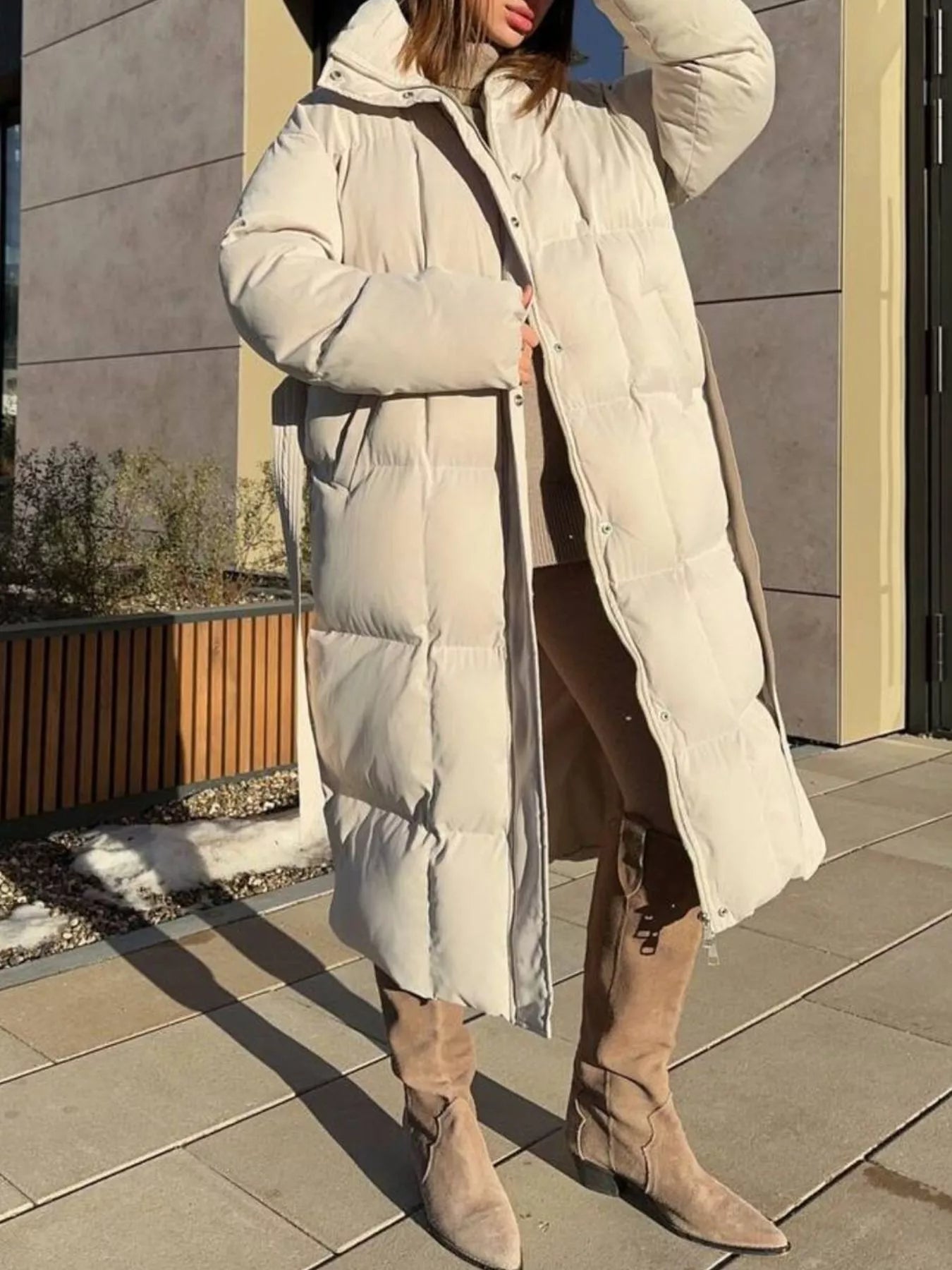 Longline Padded Winter Coat Belted worn by a woman in a stylish outdoor setting, showcasing its warm and puffy design.