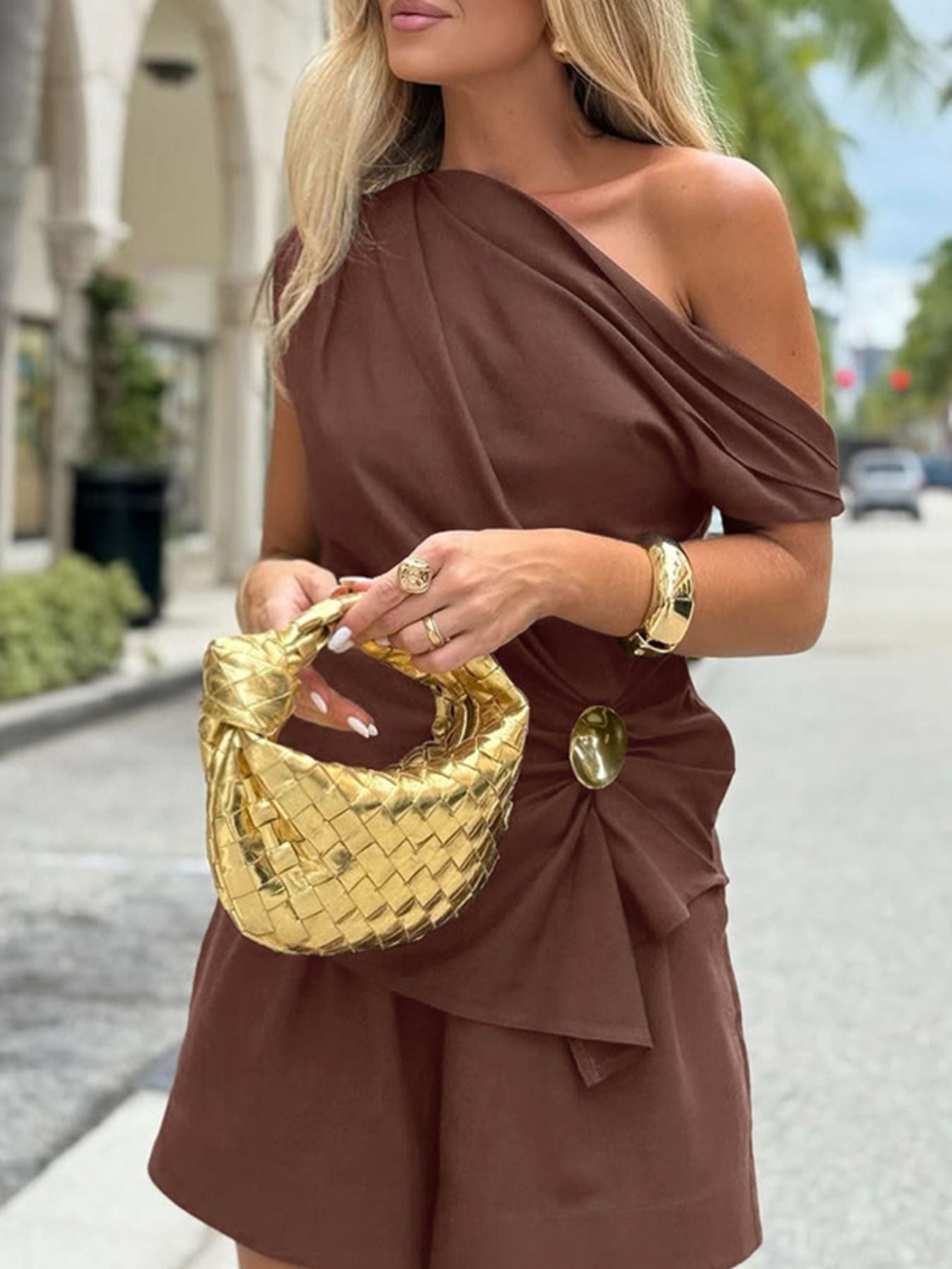 One Shoulder Top and Shorts Set stylish asymmetrical outfit with ruched design and a straw handbag.