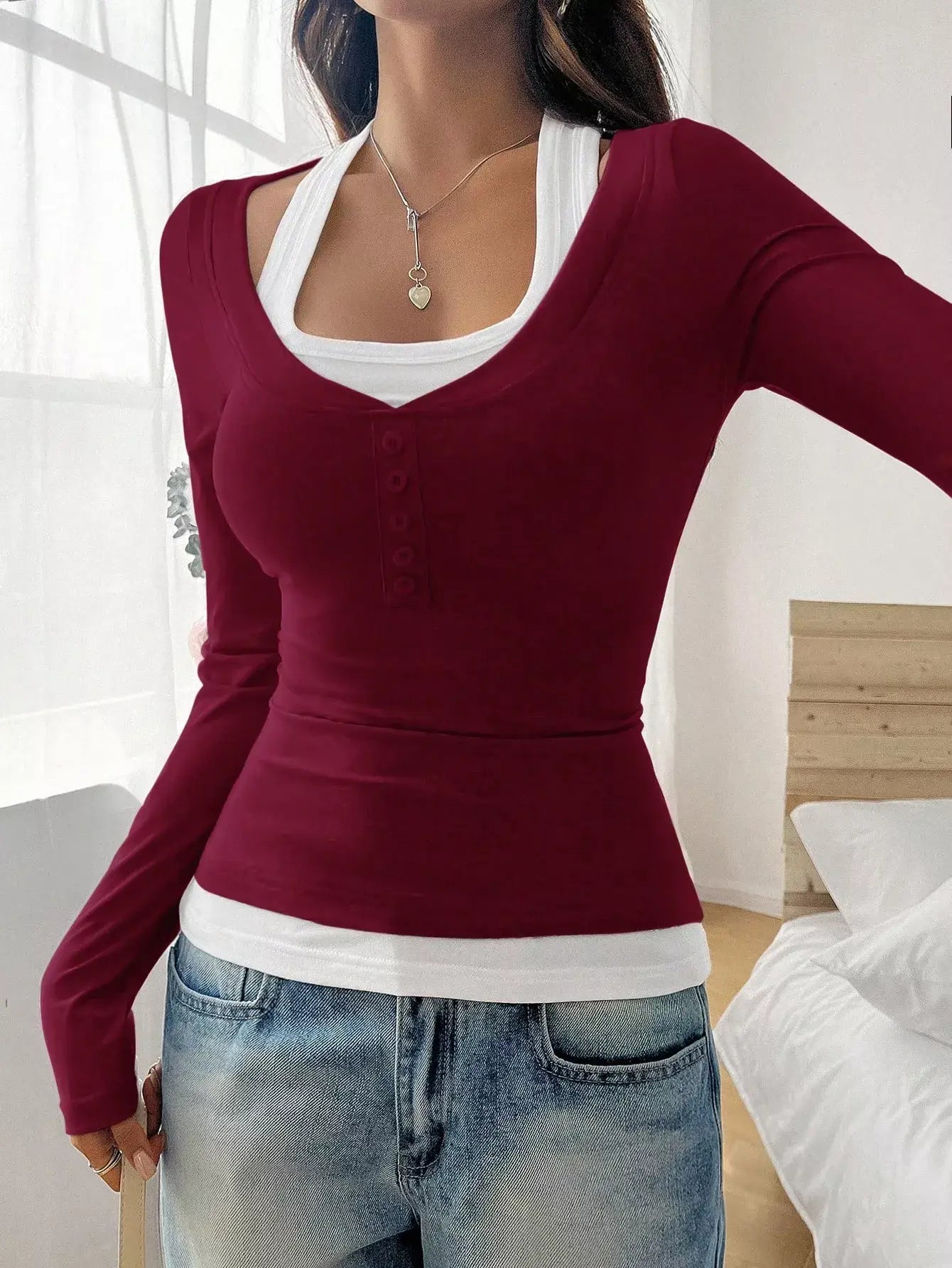 Woman wearing a chic scoop neck long sleeve t-shirt in burgundy, styled with casual jeans, showcasing everyday comfort.