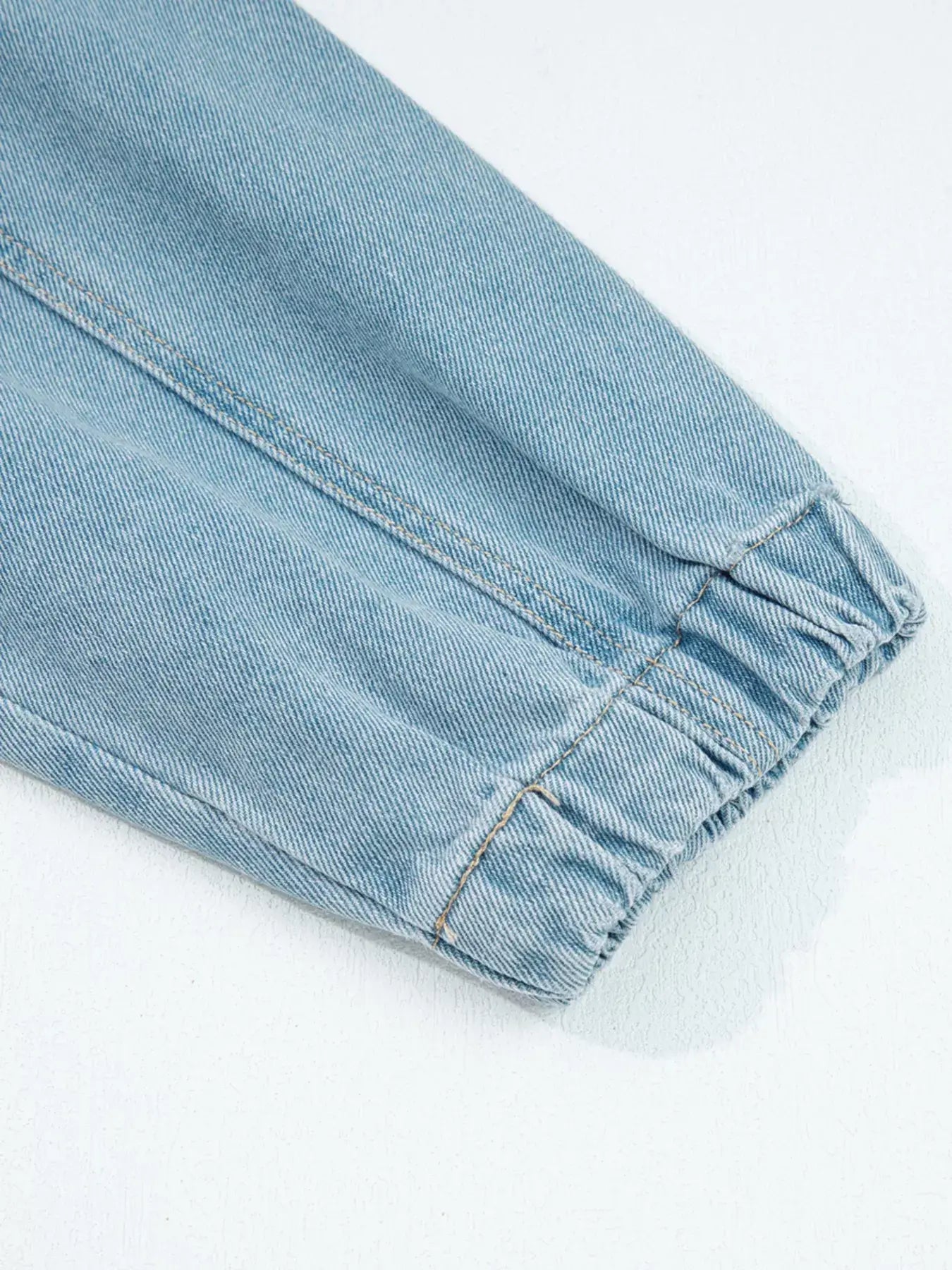 Close-up of the elastic cuff detail on a light blue zip-up denim jacket.
