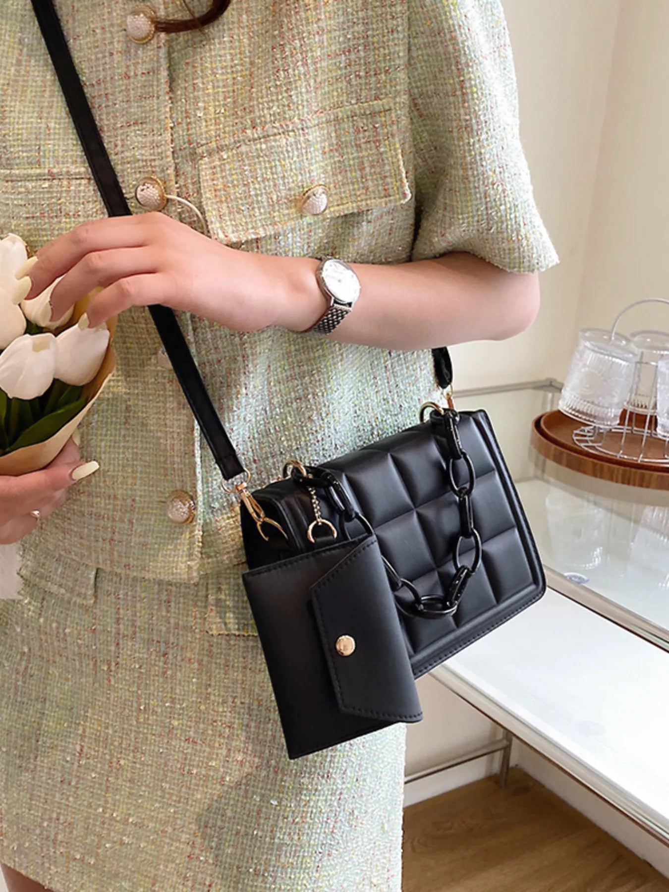 Woman holding a Quilted Chain Strap Crossbody Bag in black PU leather, styled with a chic outfit.