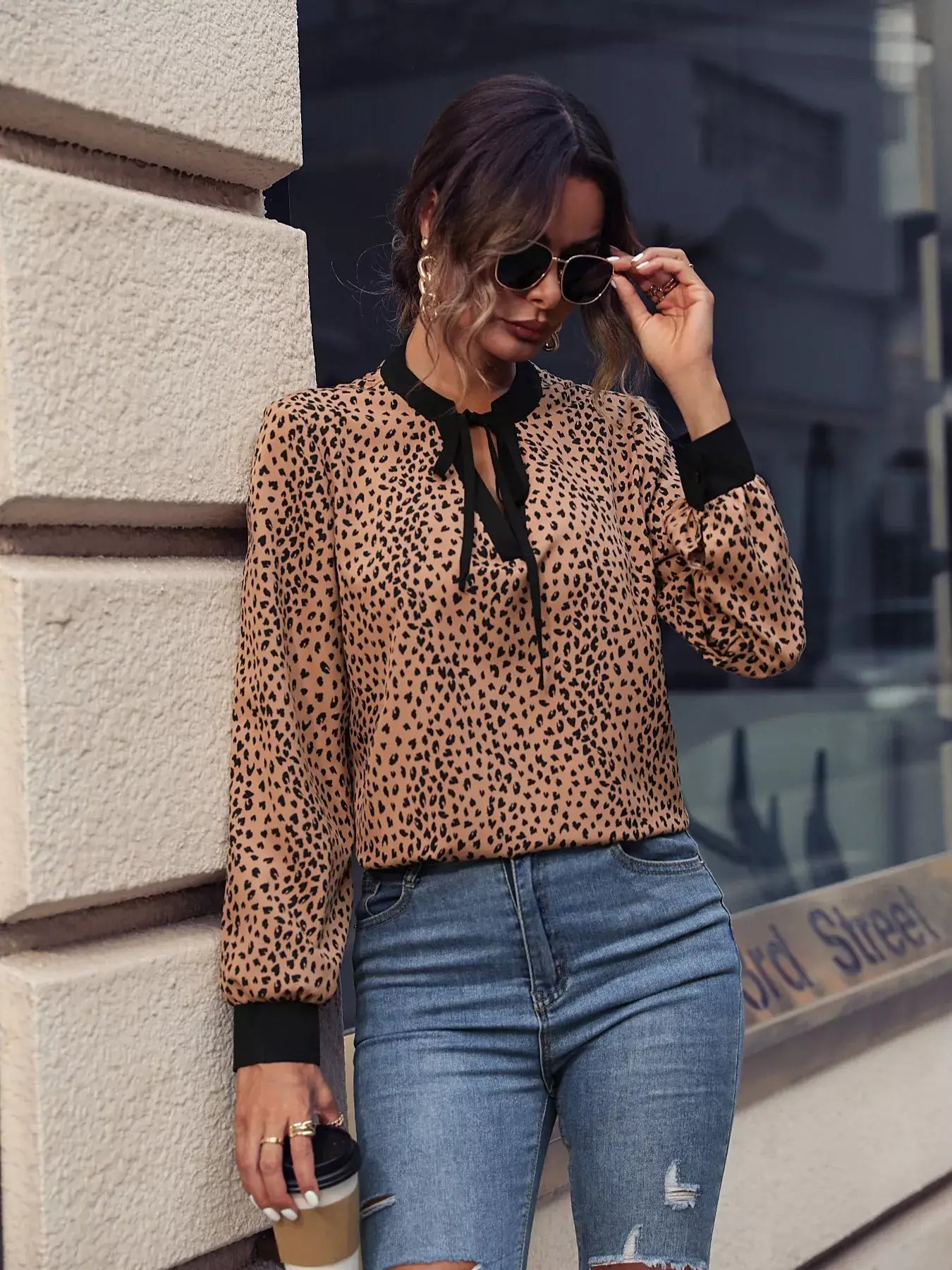 Model wearing an animal print contrast trim tie front blouse with sunglasses and coffee, stylish streetwear.