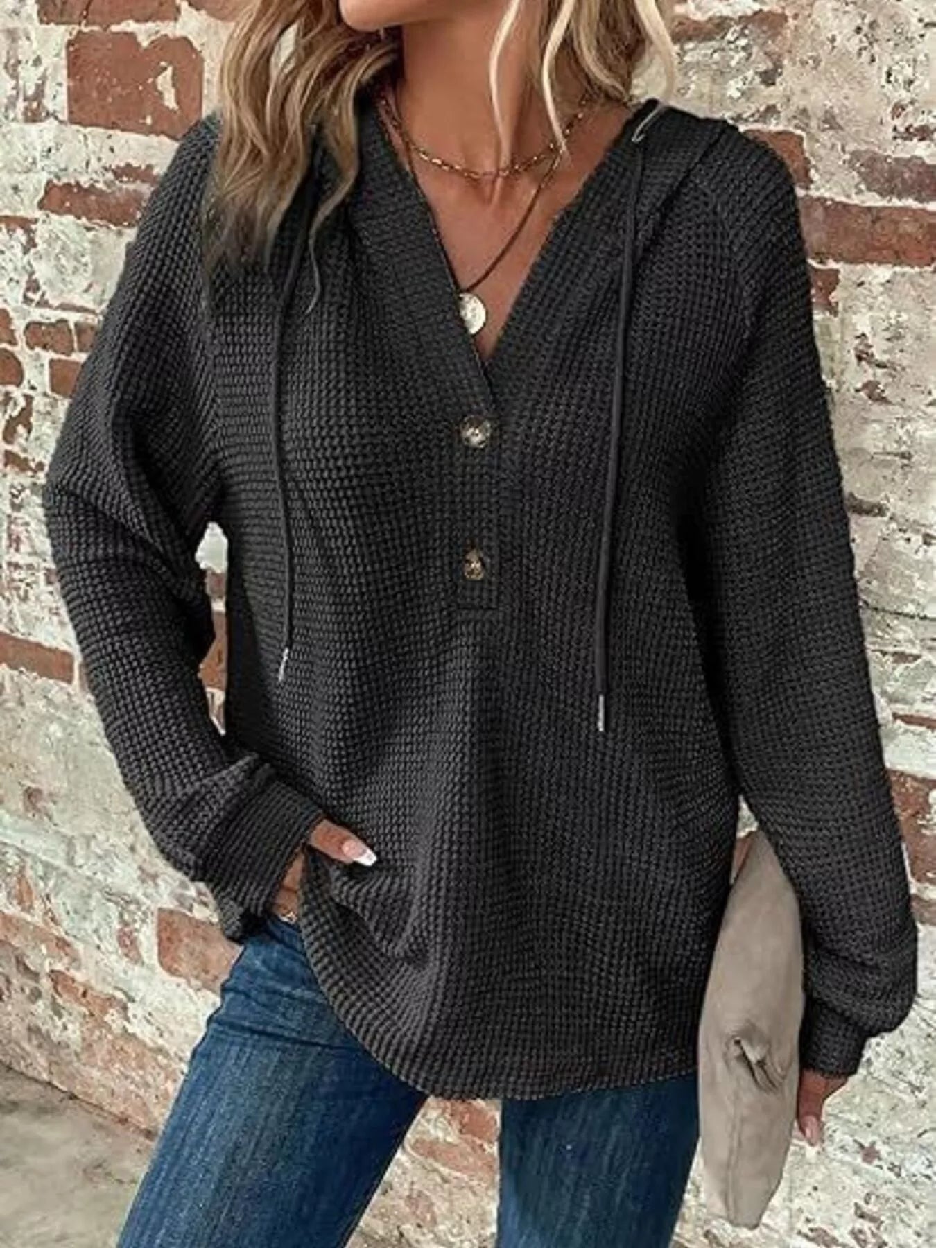Full Size Button Detail Waffle Knit Hoodie Plus Size in black worn by a woman against a brick wall.