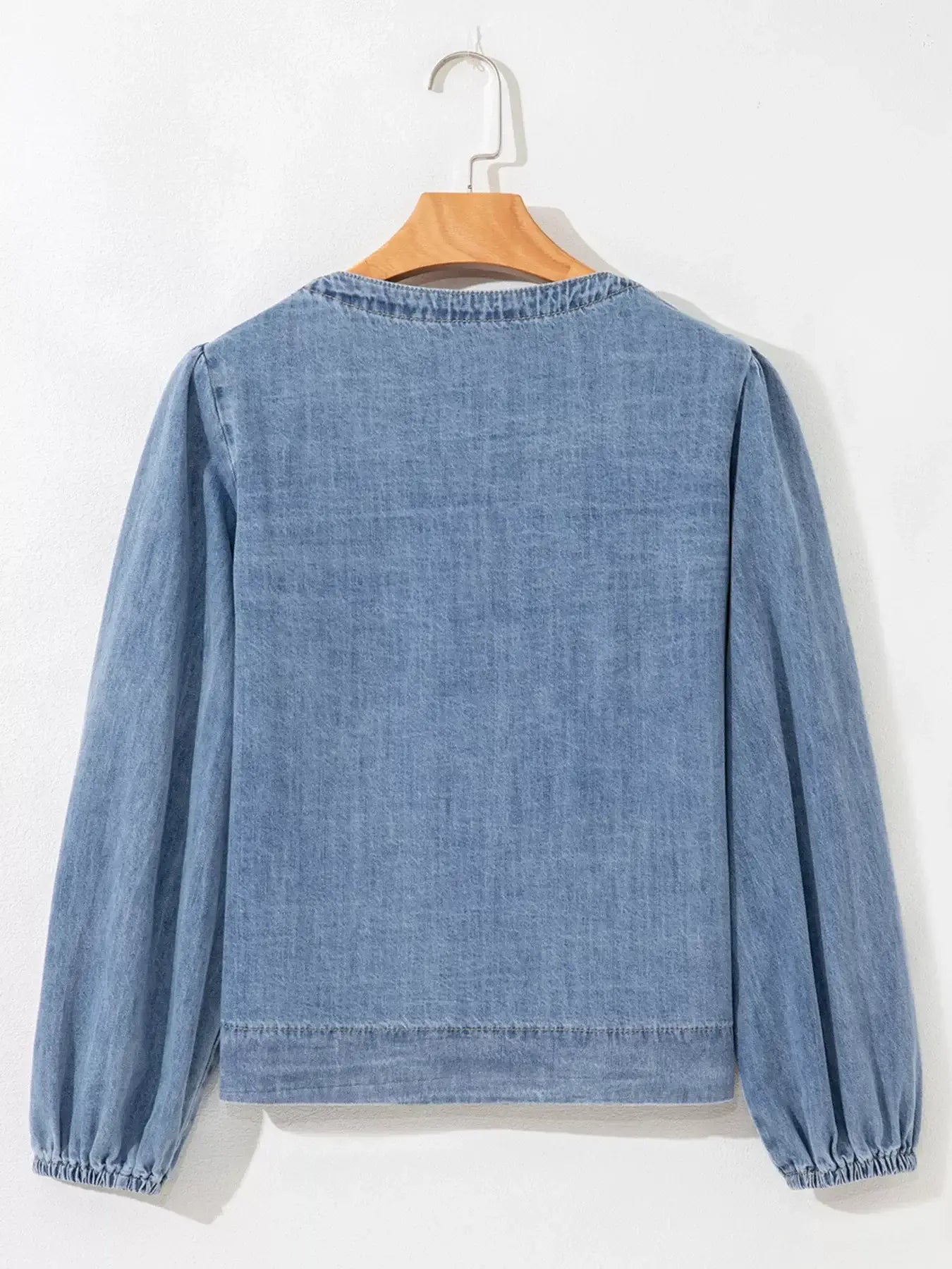 Back view of a stylish denim blouse with puff sleeves, showcasing a casual yet chic design.