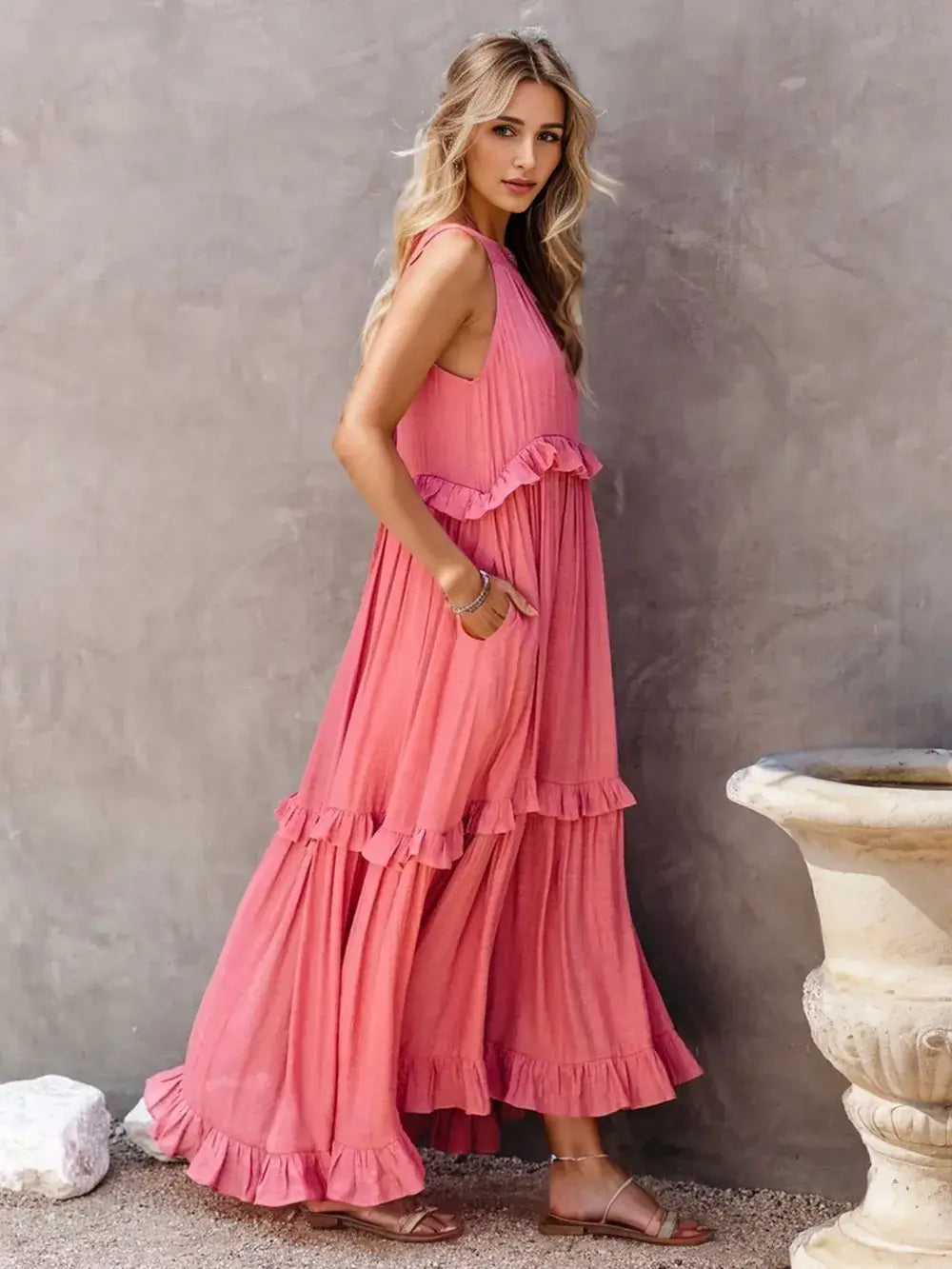 Ruffled Sleeveless Tiered Maxi Dress with Pockets worn by a model, highlighting its elegant ruffles and pink color.
