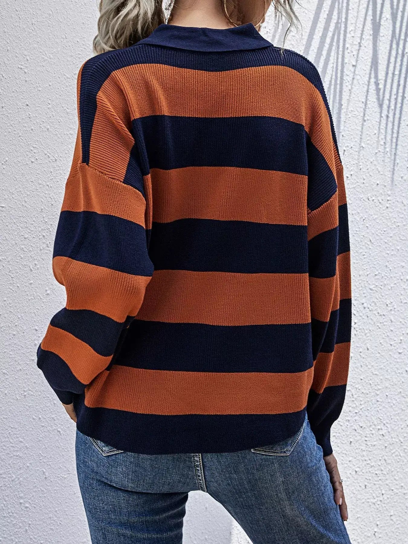 Back view of a woman wearing the Striped Button Detail Dropped Shoulder Knit Top with bold orange and navy stripes.