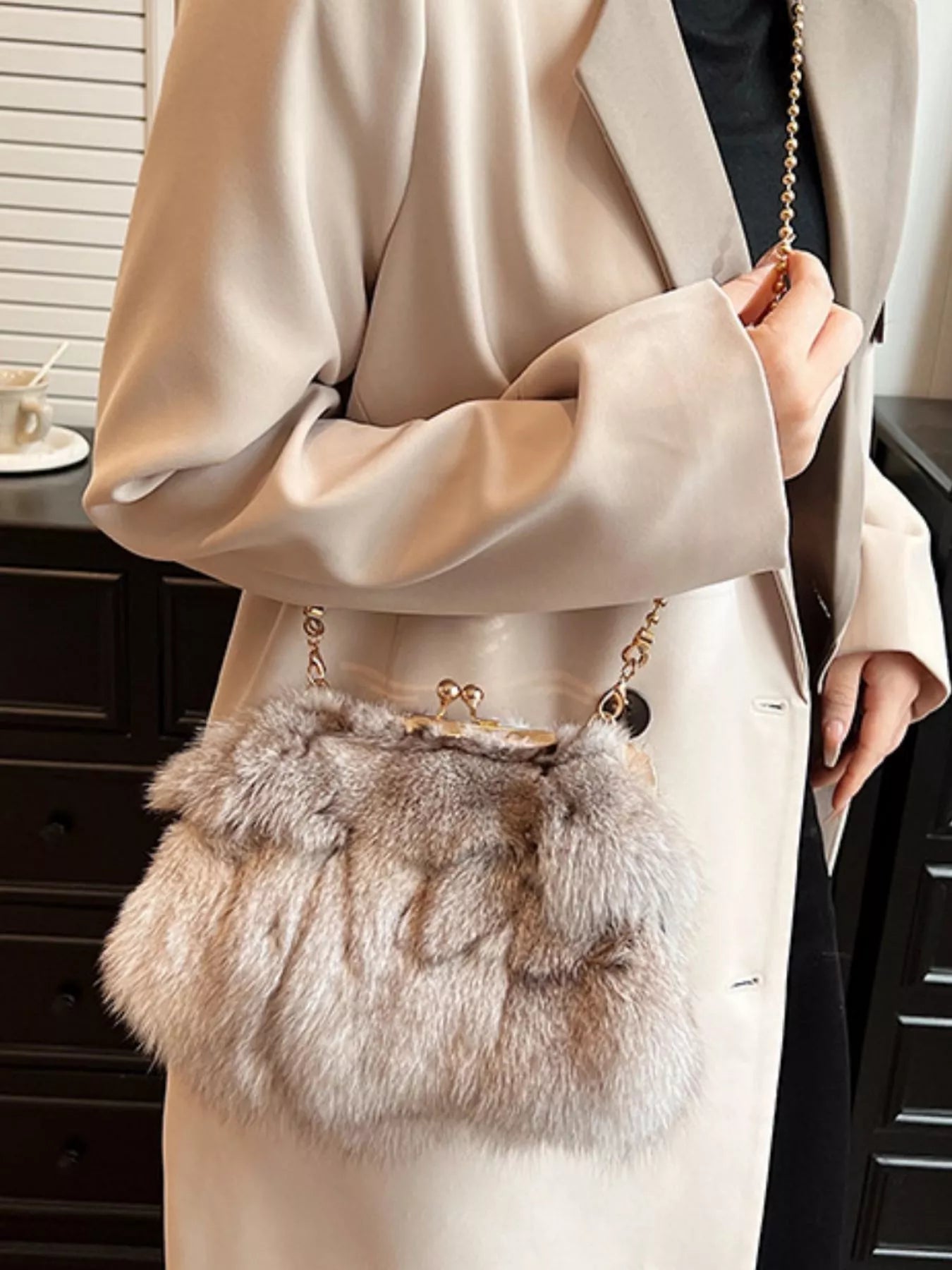 Furry Chain Crossbody Bag shown being held by a model in a stylish outfit, highlighting its luxurious fox fur material.