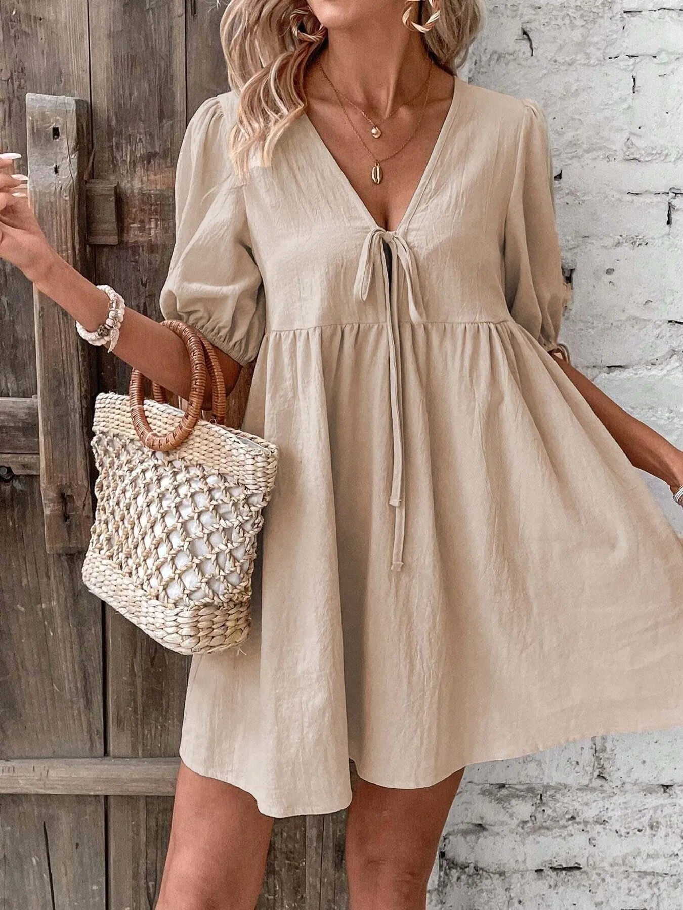 V-Neck Tie-Front Mini Dress with Puff Sleeves in beige, featuring a tied front and puff sleeves, styled with a woven bag.