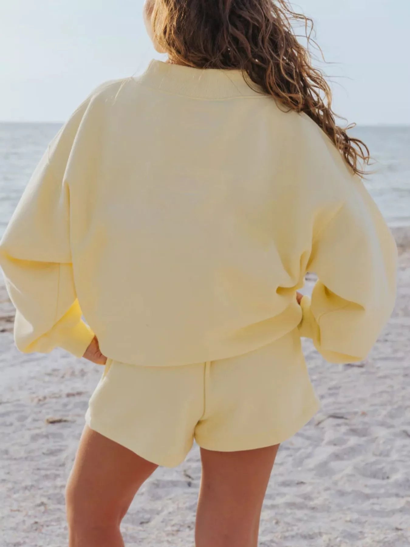 Model wearing a Relaxed Fit Round Neck Sweatshirt and Shorts Set in yellow on the beach.