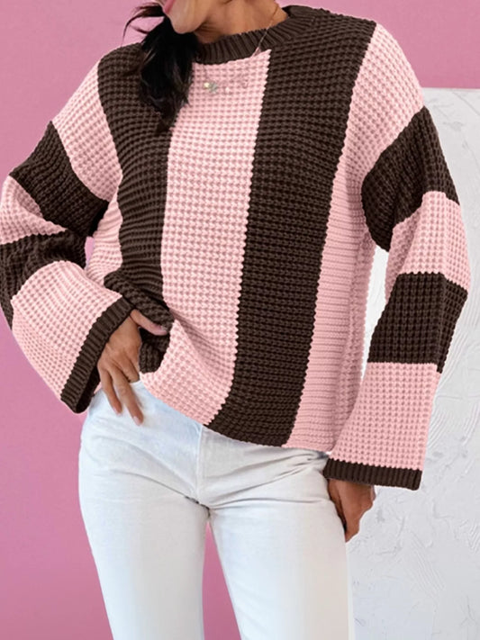Striped Color Block Waffle Knit Sweater worn with white jeans against a pink background, showcasing modern cozy style.