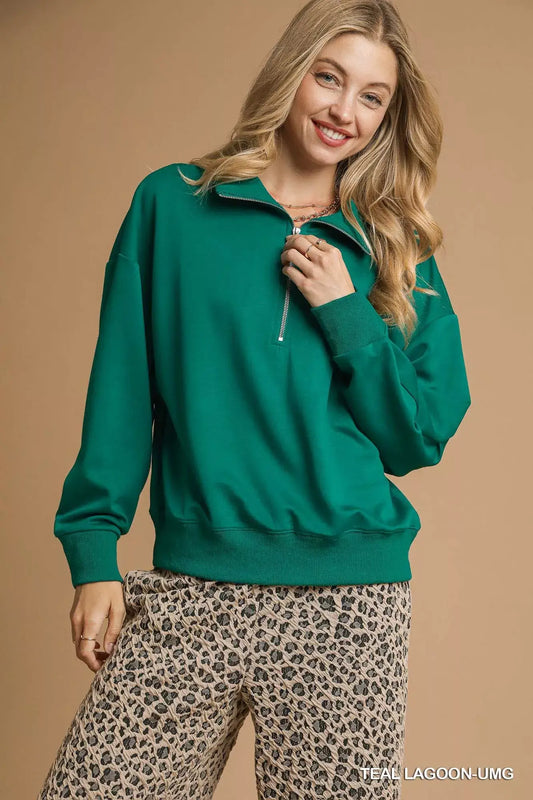 Umgee Half Zip Drop Shoulder Sweatshirt in teal lagoon worn with leopard print pants, showcasing a relaxed and stylish look.