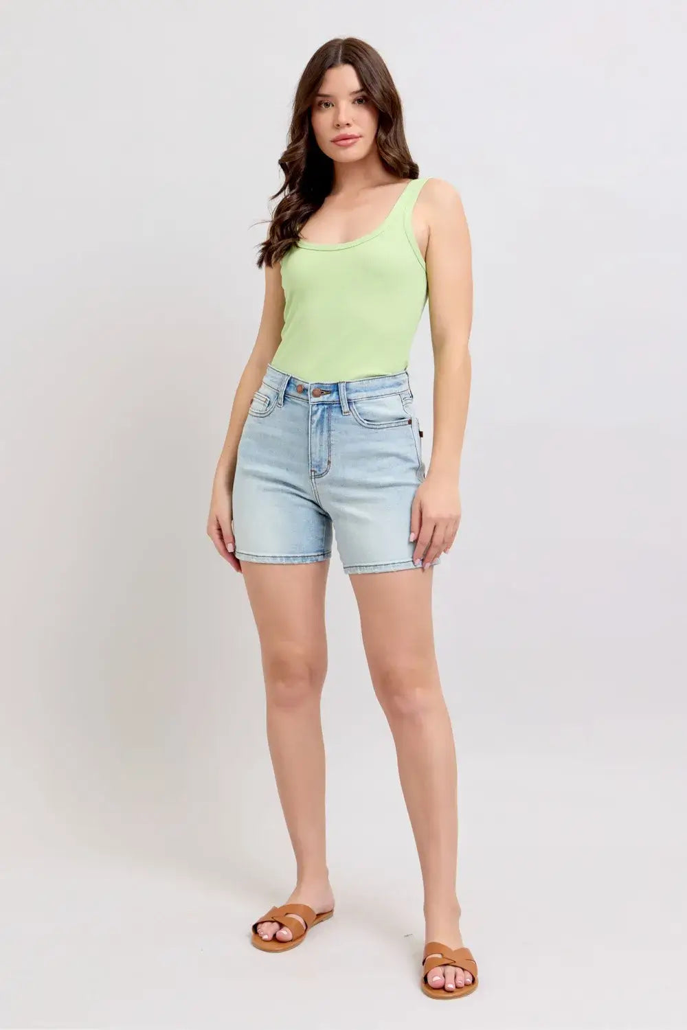 Model wearing Judy Blue Plus Size Denim Shorts with 2 buttons and pockets, paired with a green tank top.