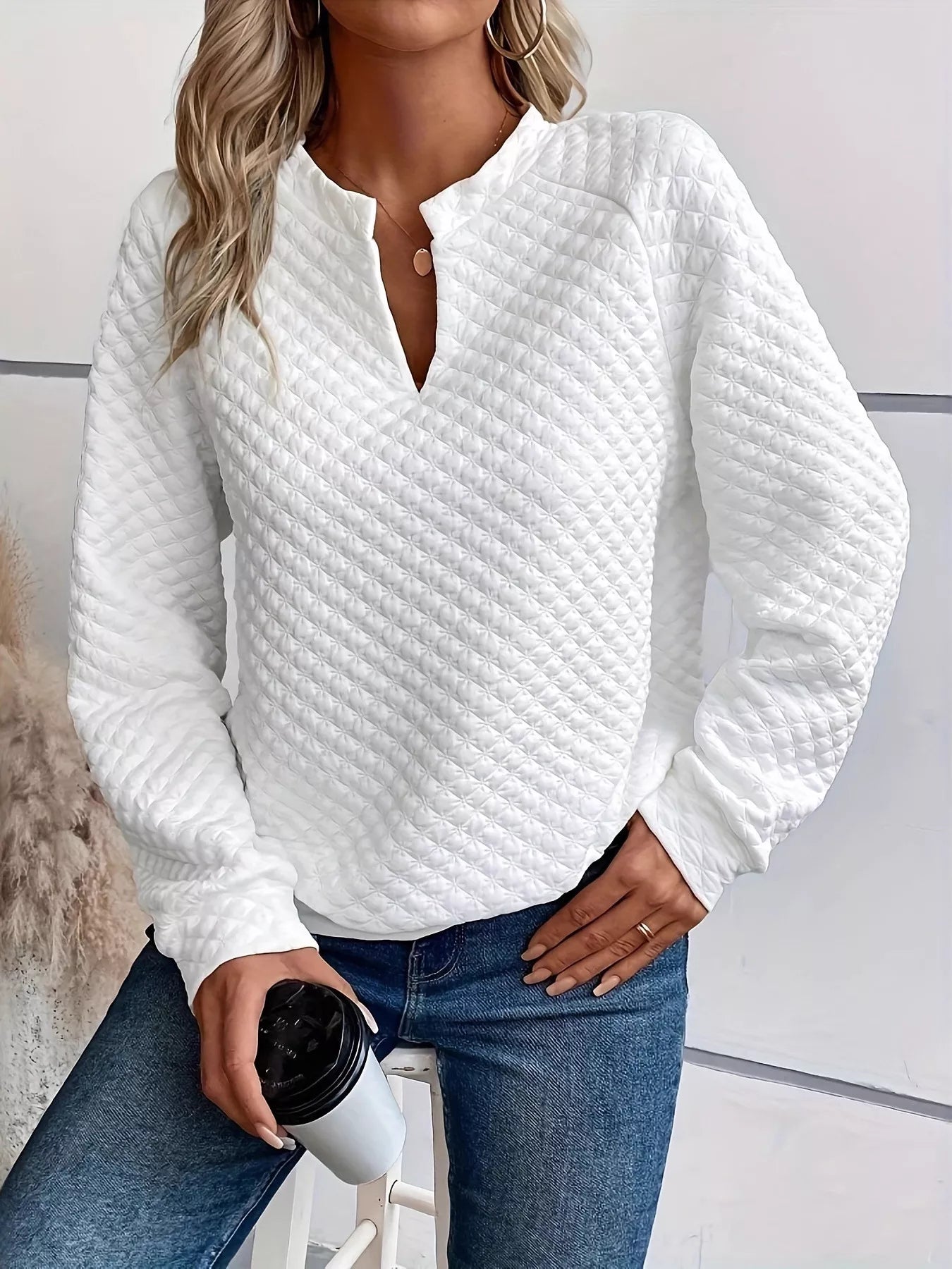 Model wearing a Quilted Texture Long Sleeve Sweatshirt with Notched Neck, holding a coffee cup, styled with jeans.