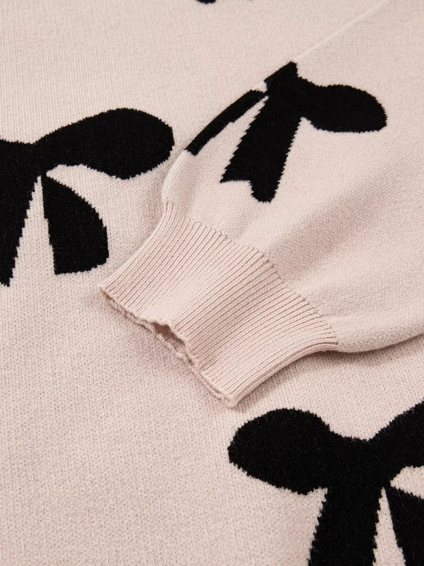 Close-up of the pearl embellished bow pattern loose sweater showcasing the intricate bow designs and cozy knit texture.