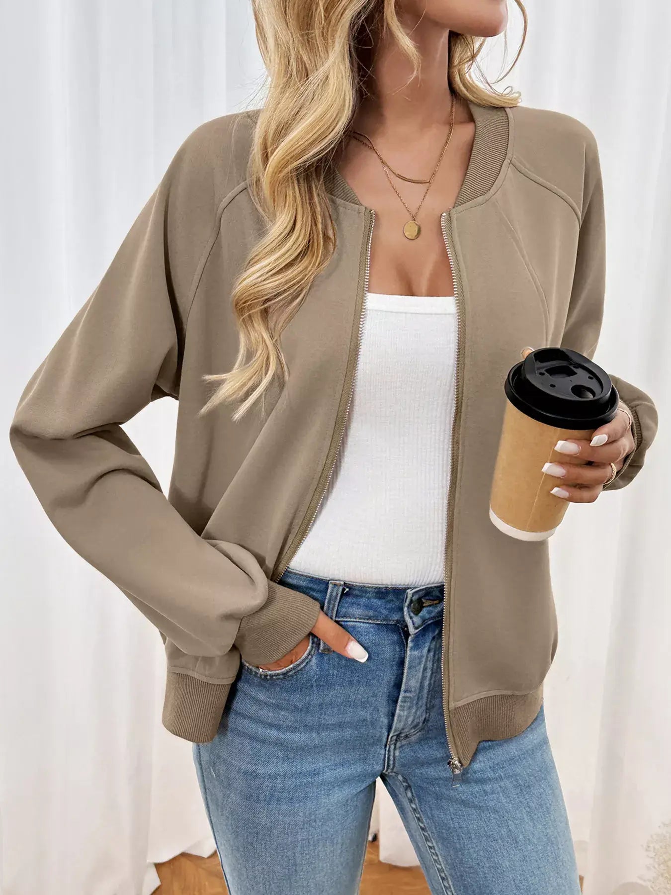 Woman wearing a Zip Up Raglan Sleeve Jacket, stylishly holding a coffee, showcasing a comfortable fit.