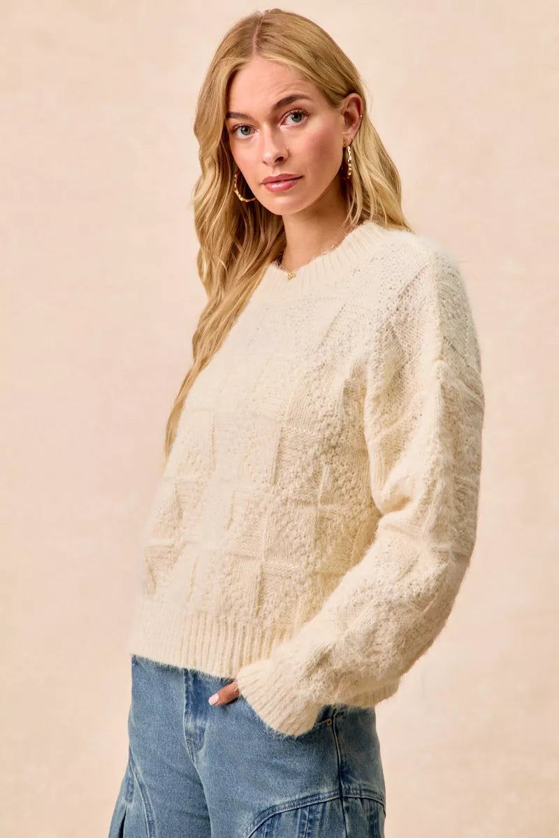 Model wearing the BiBi Checker Board Drop Shoulder Sweater in ivory, showcasing its relaxed fit and trendy design.