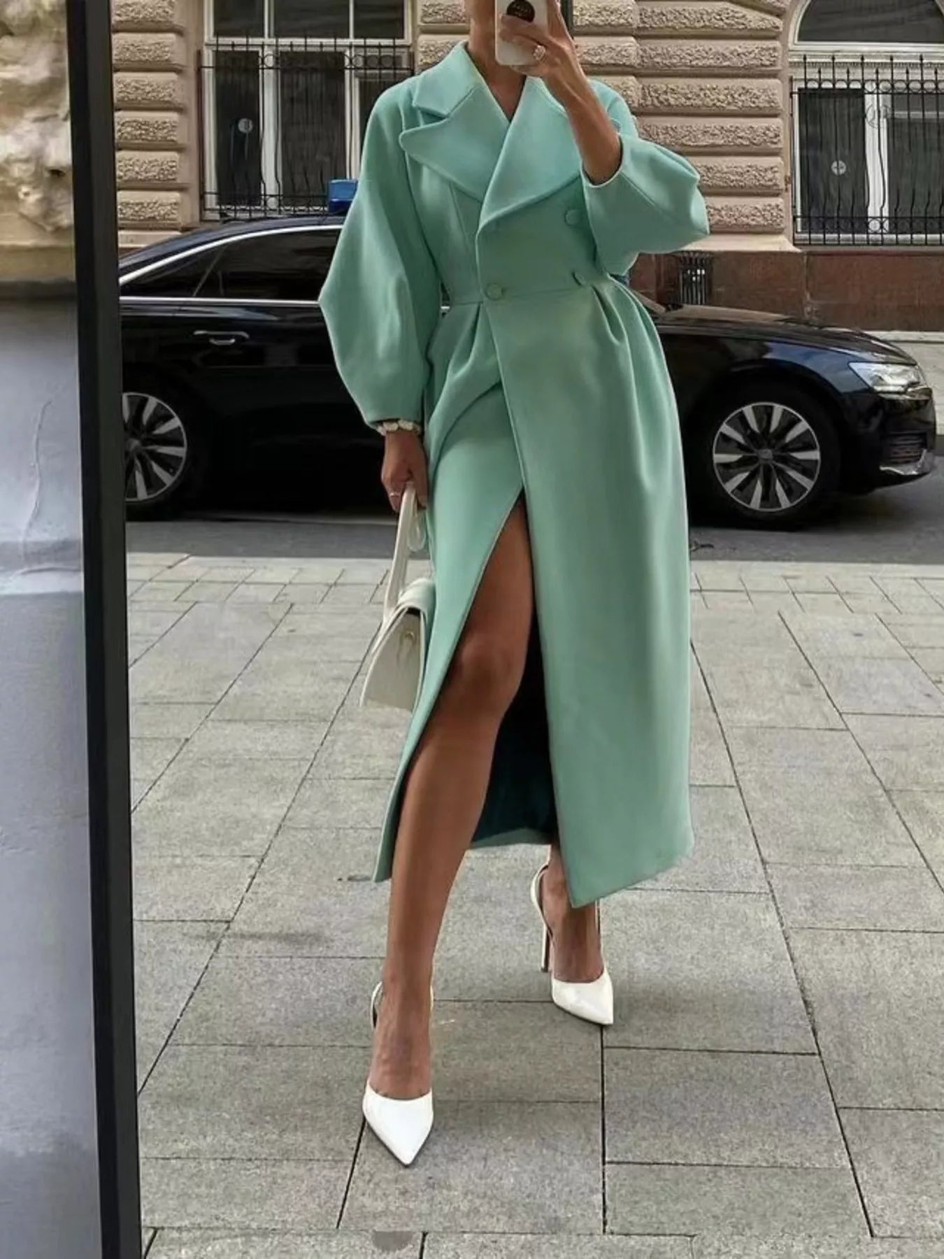 Double-Breasted Longline Coat in mint green styled with high heels, featuring a stylish slit and elegant tailored silhouette.