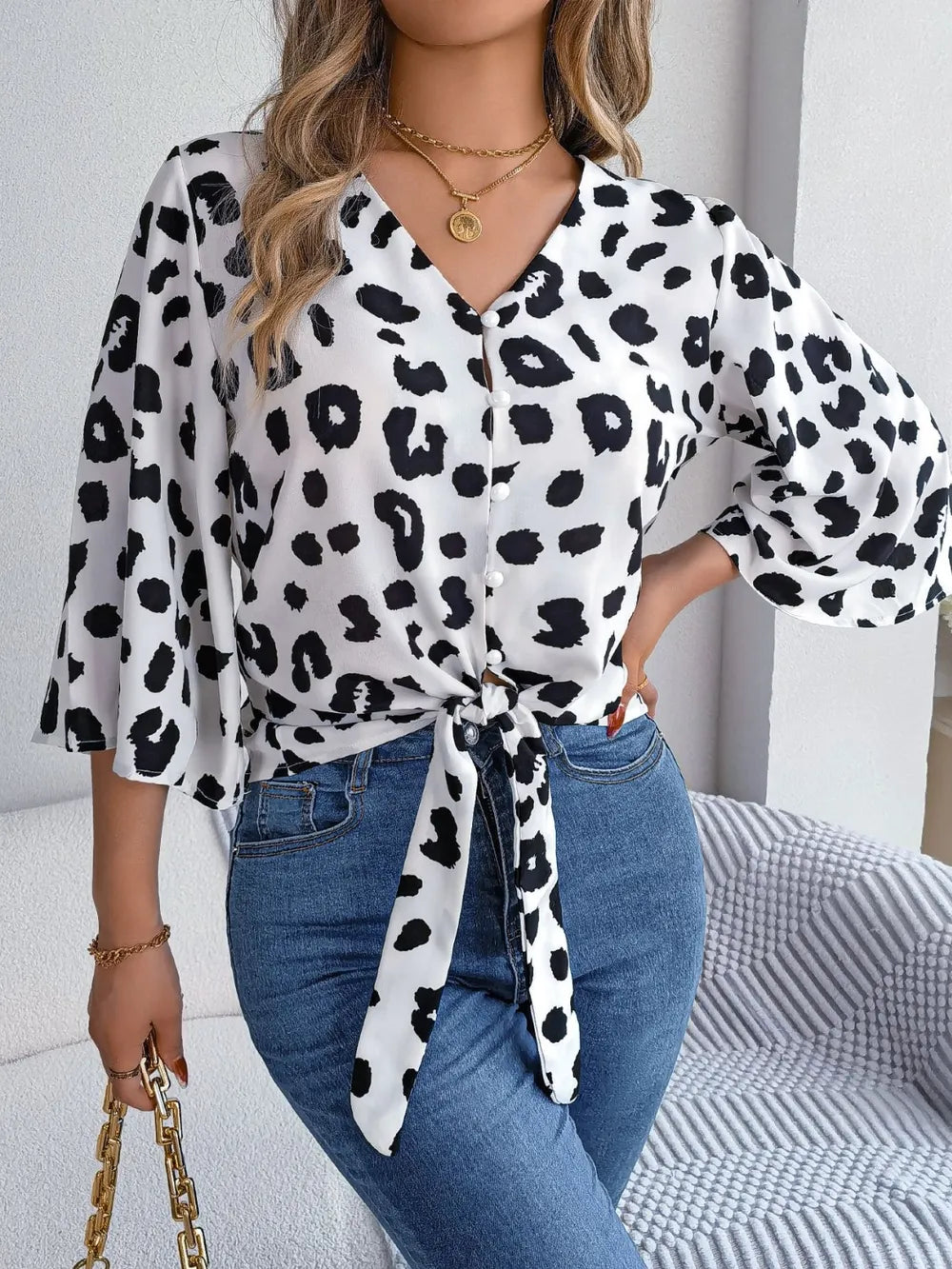 Tied Button Up Leopard V-Neck Blouse displayed on a model with a tied front and stylish jeans, showcasing a chic look.