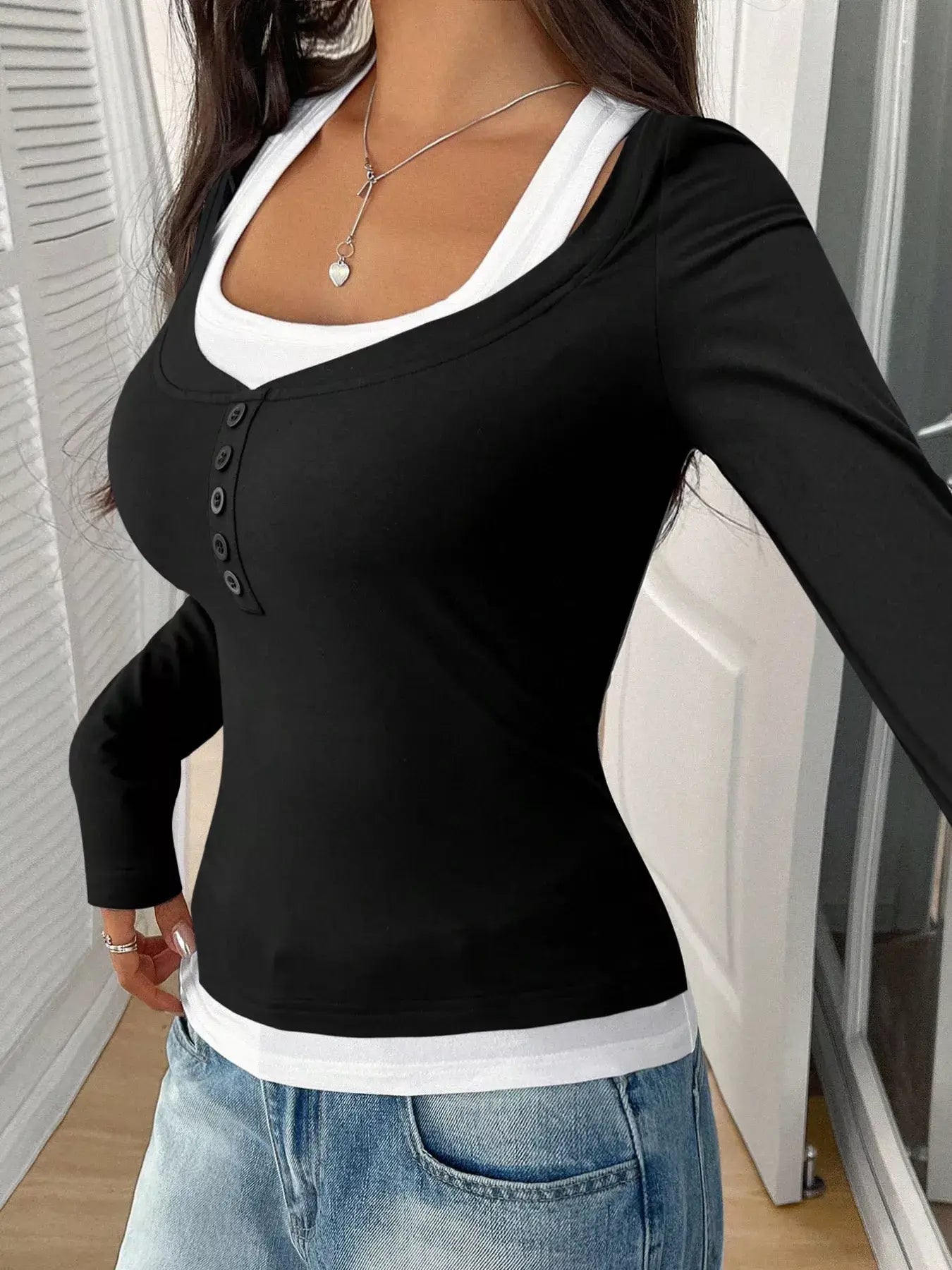 Chic scoop neck long sleeve t-shirt in black with buttons, paired with a white tank top for a stylish, casual look.