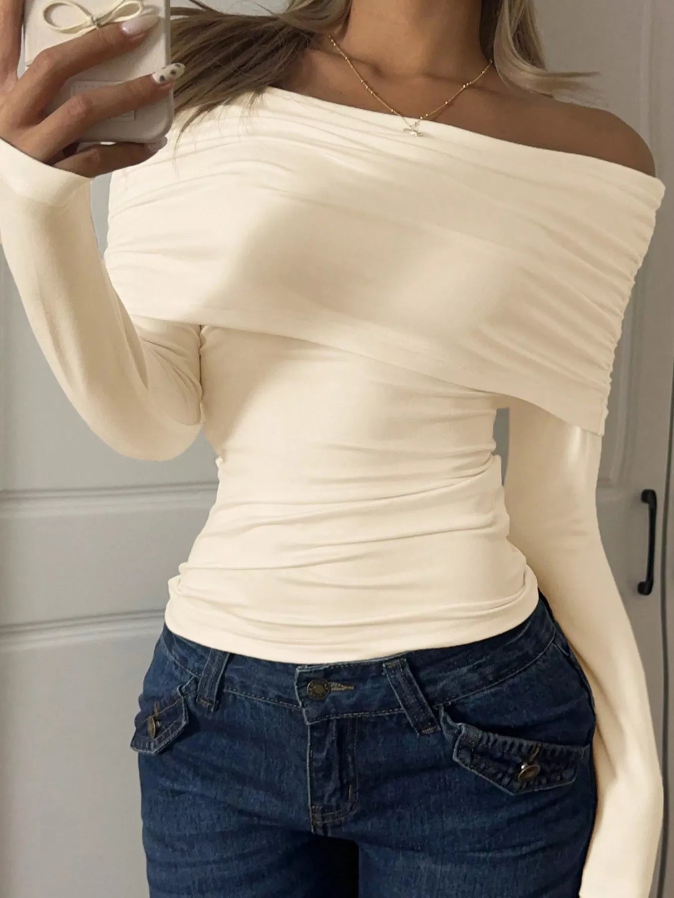 Off-Shoulder Ruched Long Sleeve T-Shirt for Modern Women in cream color, paired with blue denim jeans.