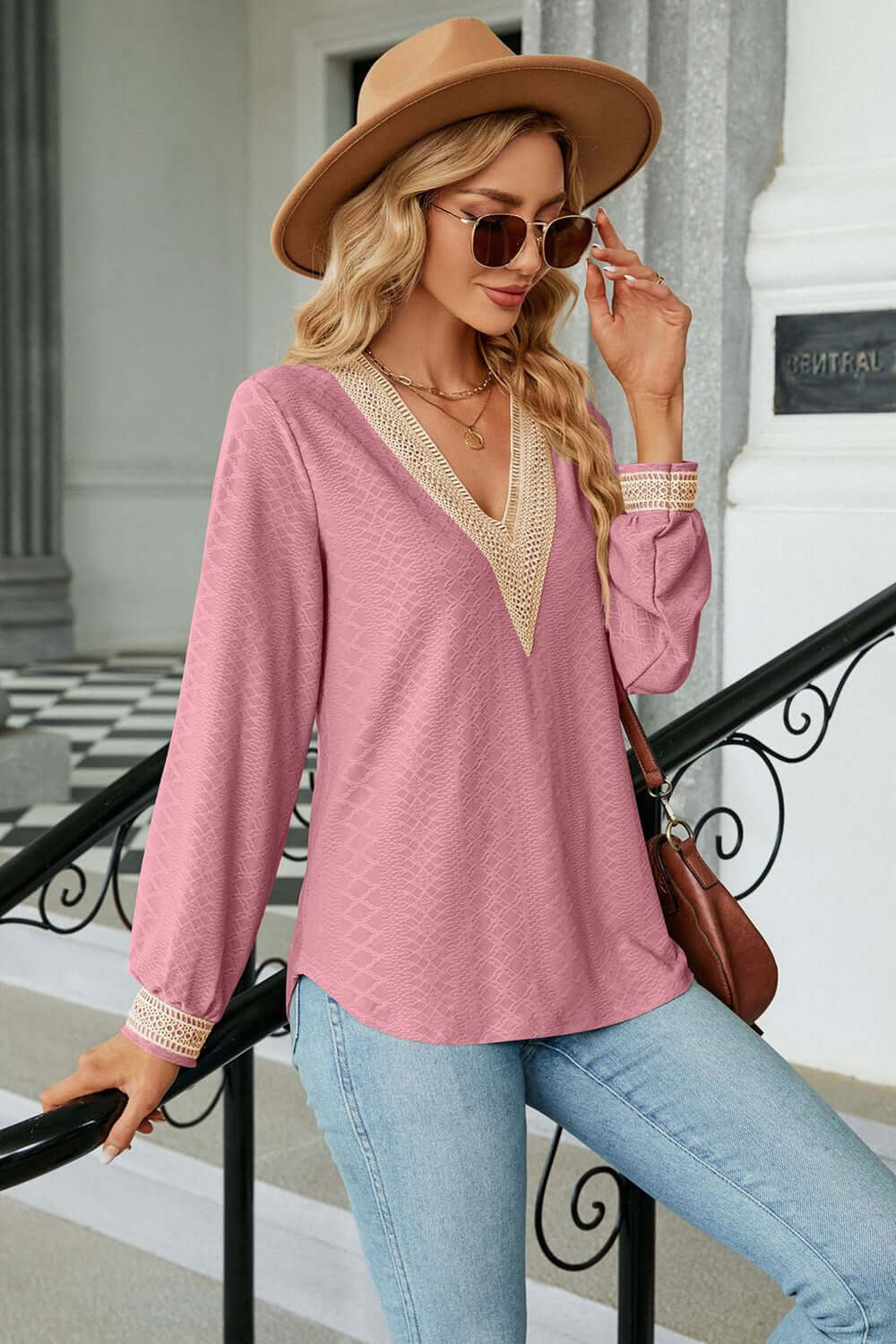 Woman wearing a stylish V-Neck Long Sleeve Blouse in pink, paired with jeans and a hat.