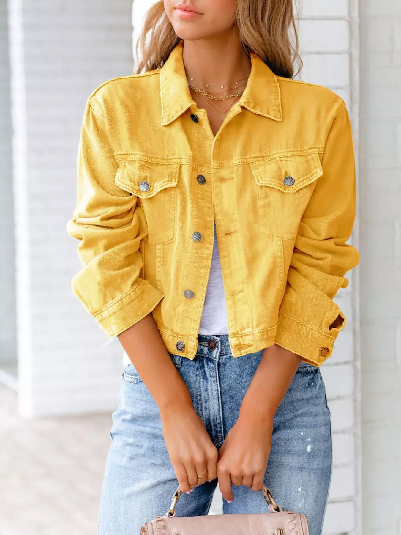 Women wearing a stylish yellow button-up denim jacket over a white top and blue jeans in a casual setting.
