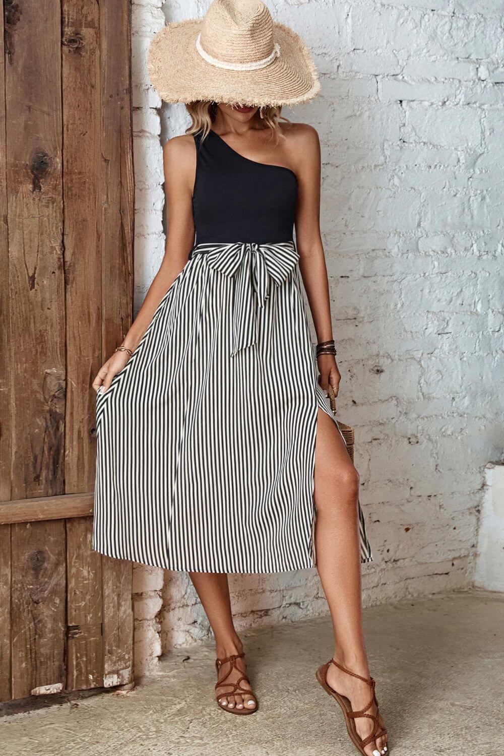 Woman wearing a Perfee Striped One-Shoulder Slit Dress with a straw hat, showcasing a chic casual style.