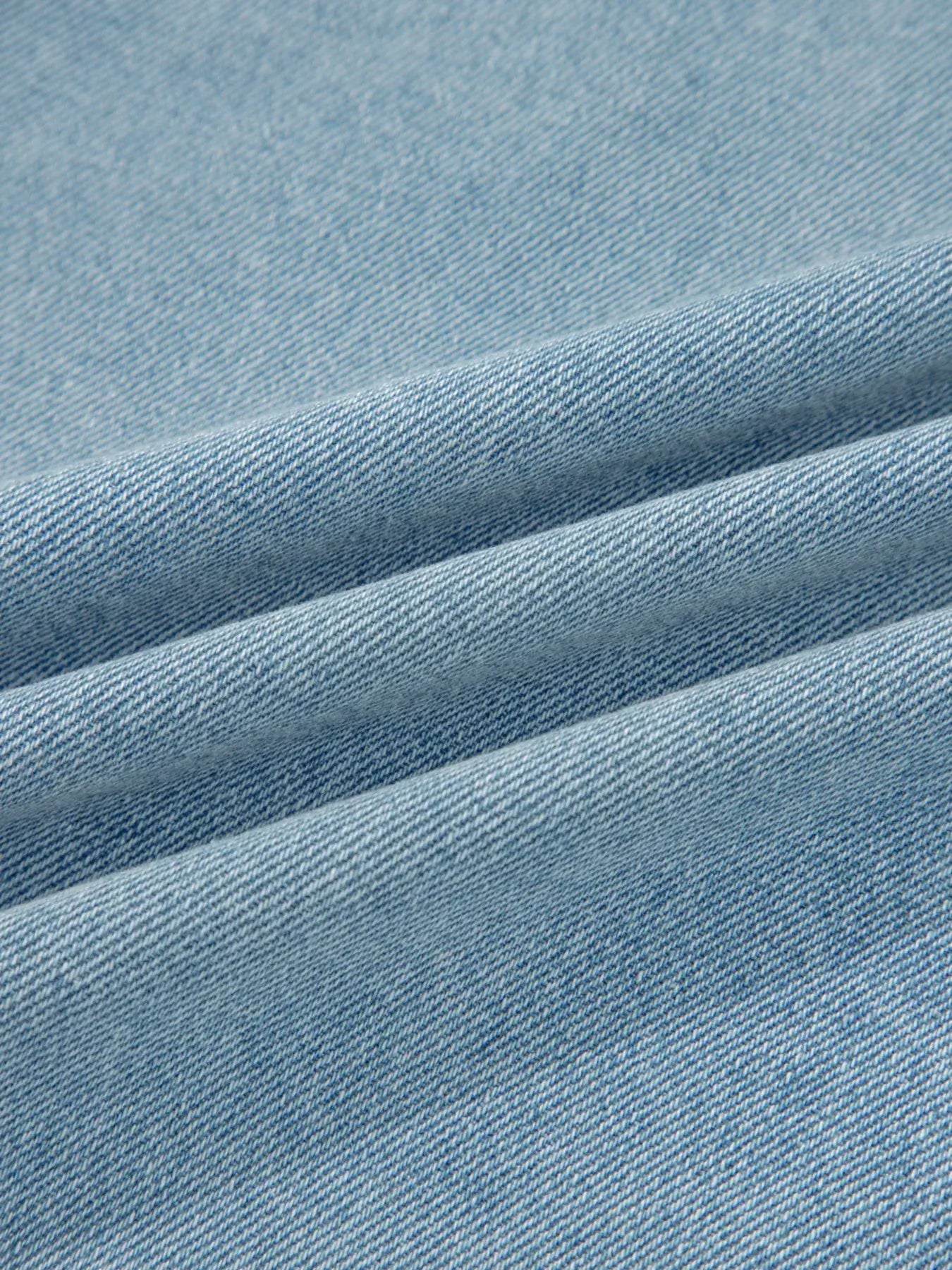 Close-up of soft, light blue denim fabric, showcasing its texture and weave for stylish clothing.