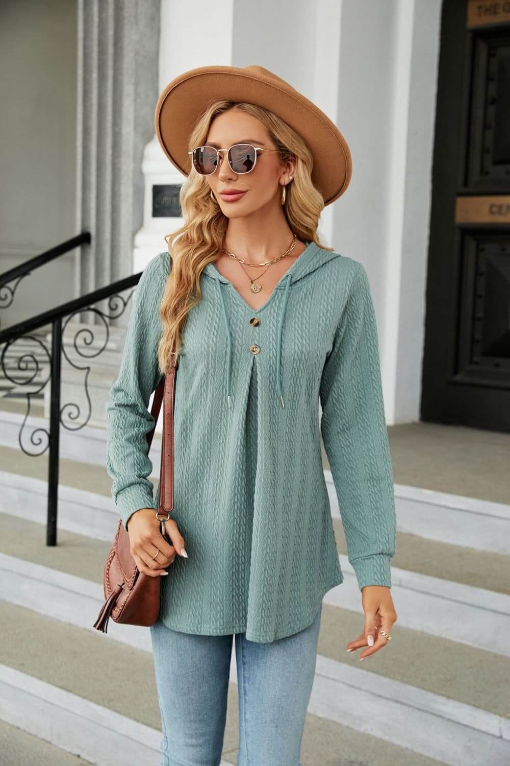 Model wearing a Long Sleeve Hooded Blouse in teal with sunglasses and a hat, showcasing a casual and cozy style.