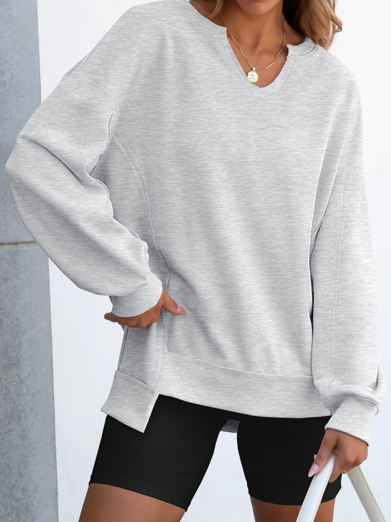Notched Long Sleeve Oversized Sweatshirt in gray worn casually with black shorts.