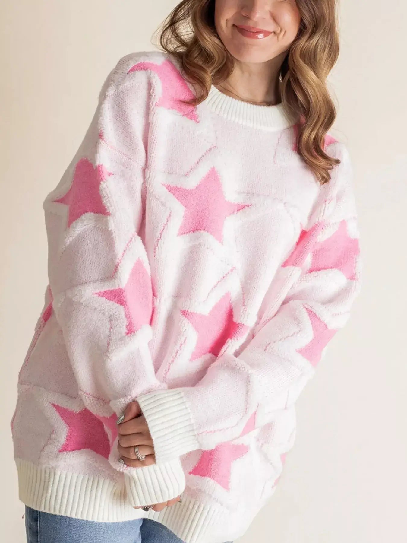 Model wearing oversized star pattern ribbed edge drop shoulder sweater in pink and white.