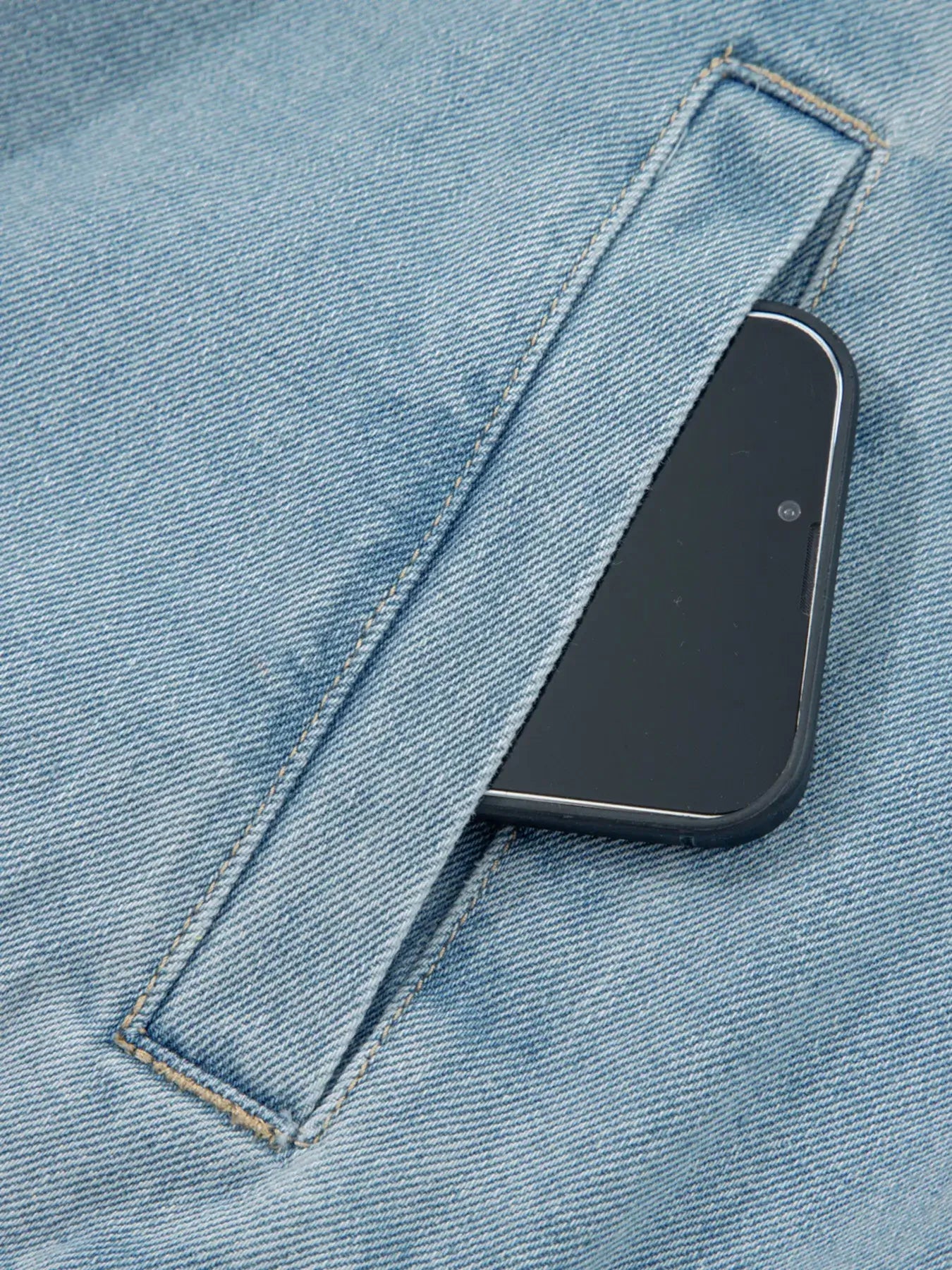 Close-up of the pocket on the Elastic Edge Collared Zip Up Denim Jacket with a smartphone partially inserted.