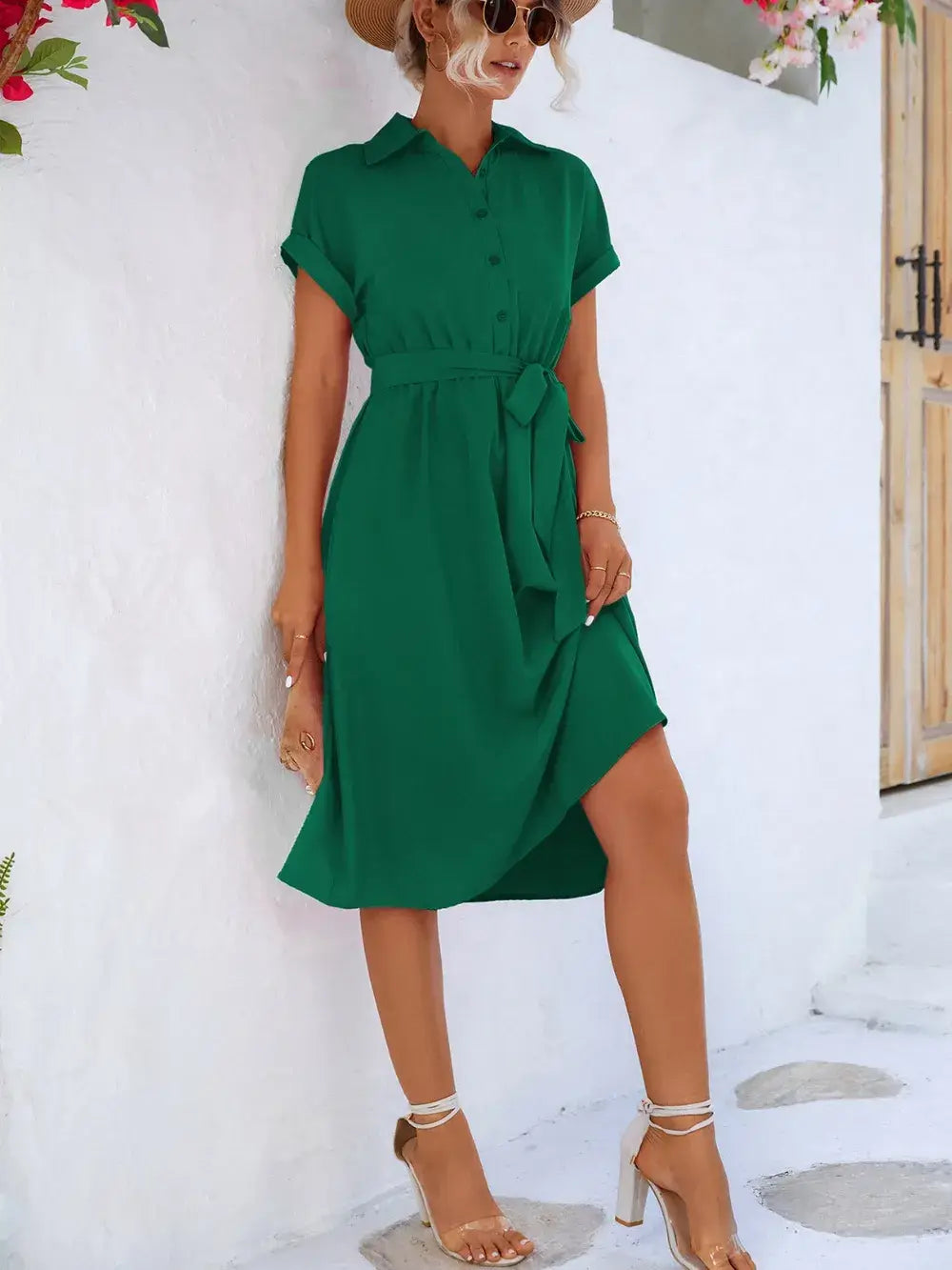 Woman in a green buttoned tie waist short sleeve dress posed outside, showcasing casual summer style.