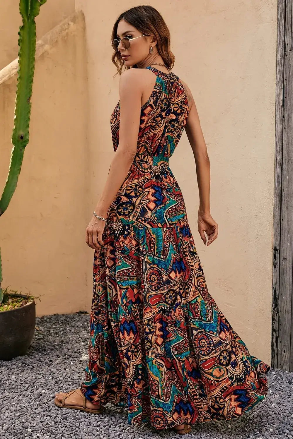Woman wearing a Tied Floral Sleeveless Dress with vibrant patterns, showing the back view in a sunny outdoor setting.