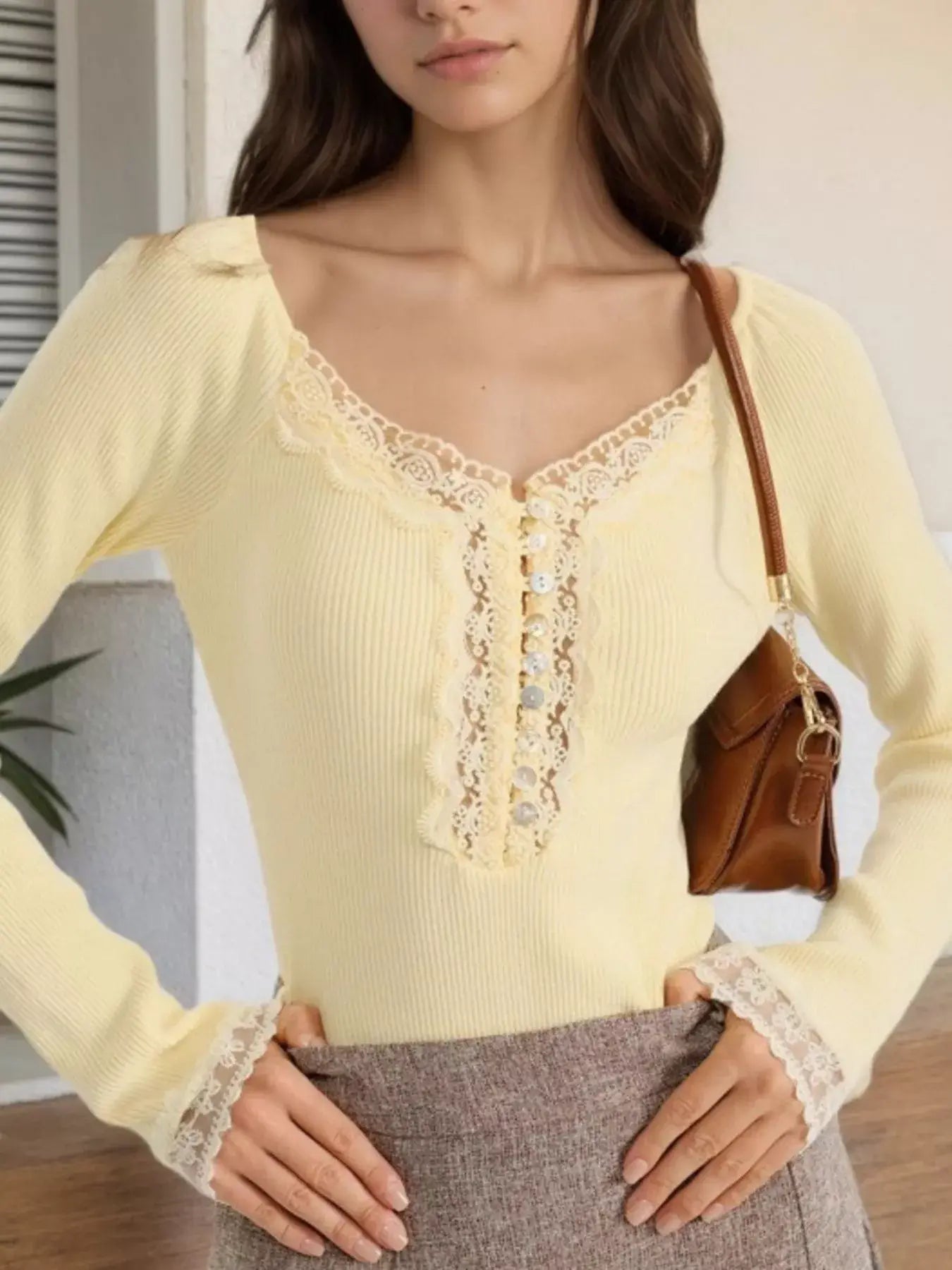 Model wearing a lace trim ribbed long sleeve T-shirt in yellow, styled with a brown handbag and chic outfit.