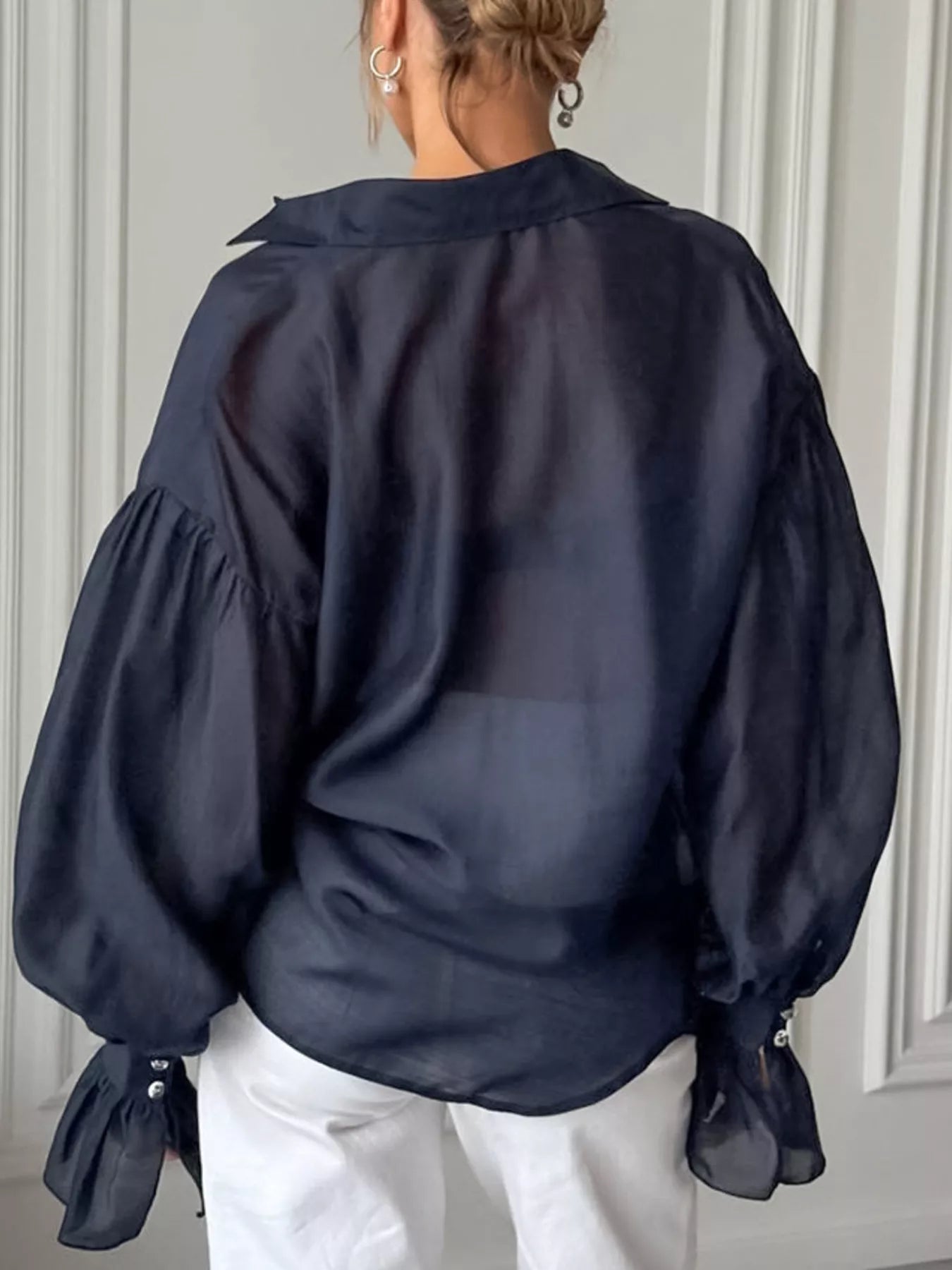 Back view of a model wearing a Button Up Flounce Sleeve Shirt in navy, showcasing its elegant flouncy sleeves.
