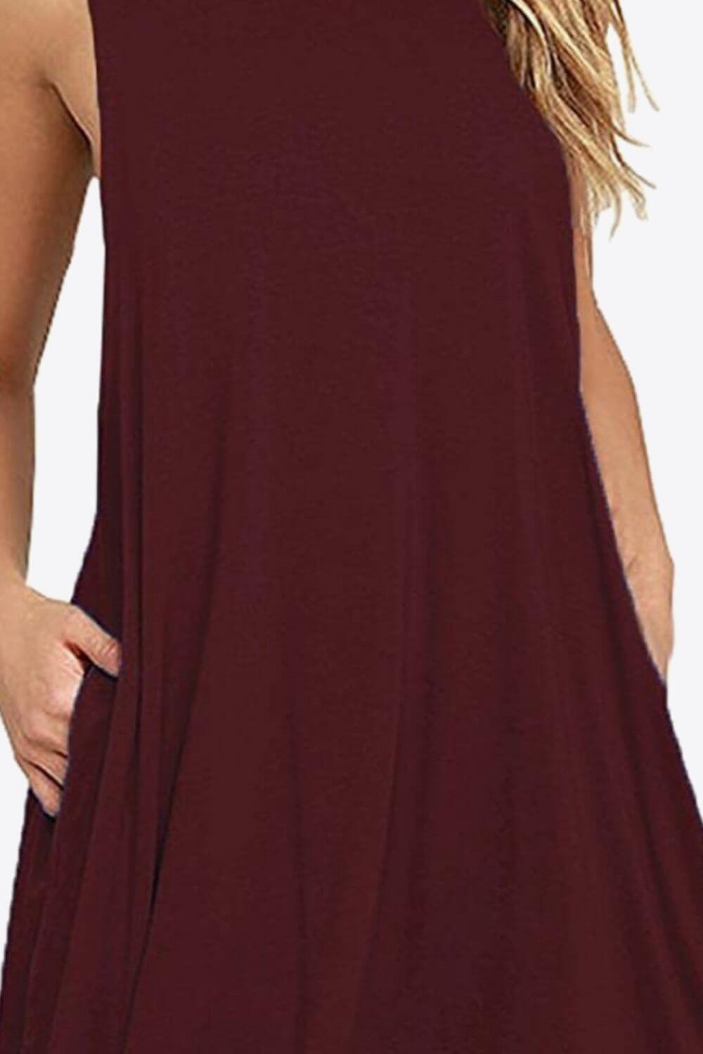 Woman wearing a sleeveless round neck mini dress in burgundy with pockets, showcasing its casual style.