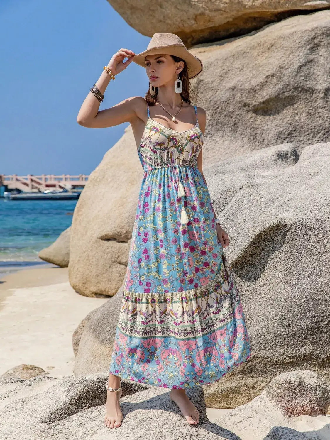 Woman wearing a Tassel Floral Print Cami Dress at the beach, showcasing a bohemian style with floral patterns.