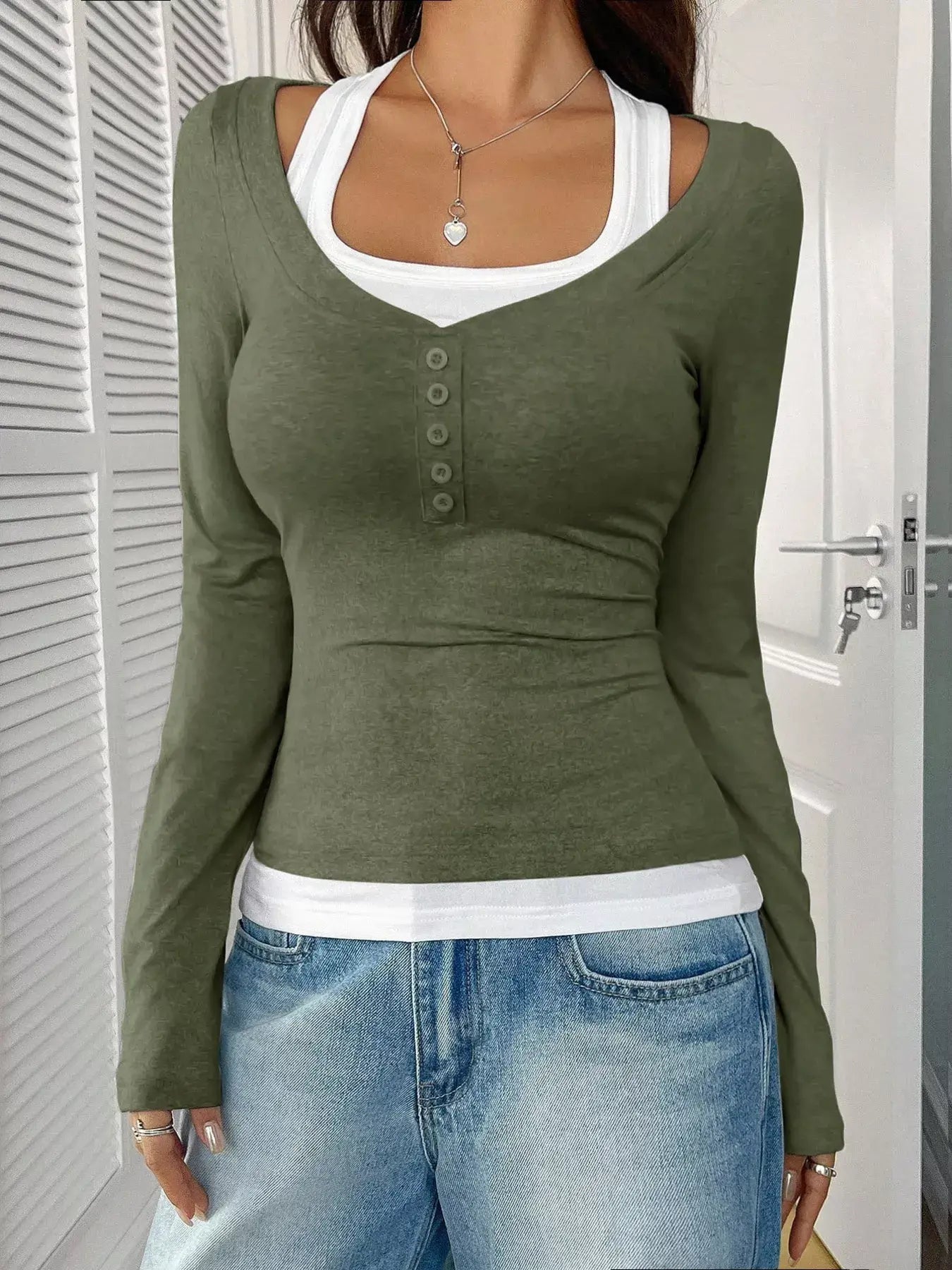 Chic scoop neck long sleeve t-shirt layered over a white tank top, paired with casual blue jeans.