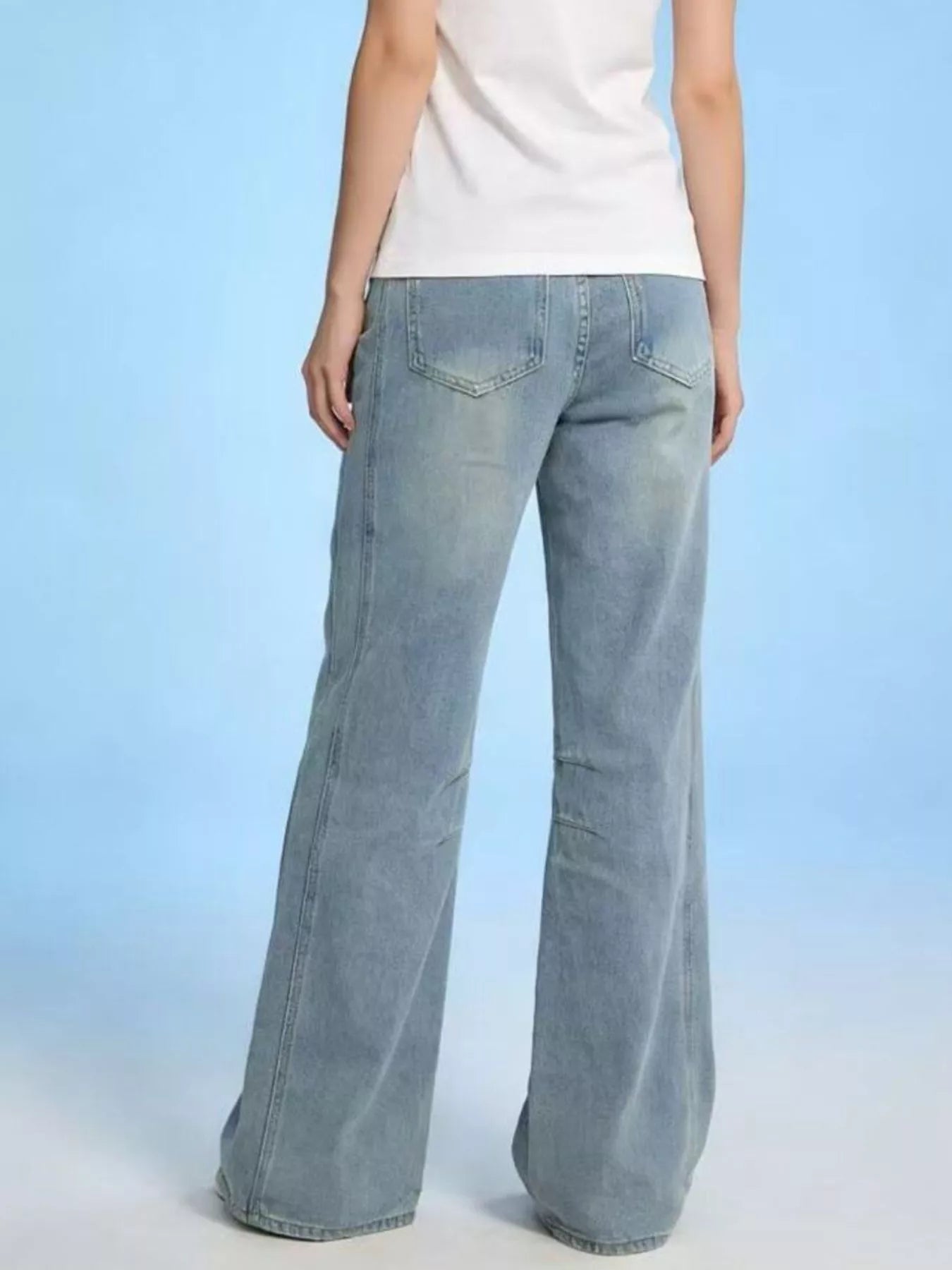 Wide Leg Wash Jeans featuring a buttoned pocketed design, shown from the back against a light blue background.