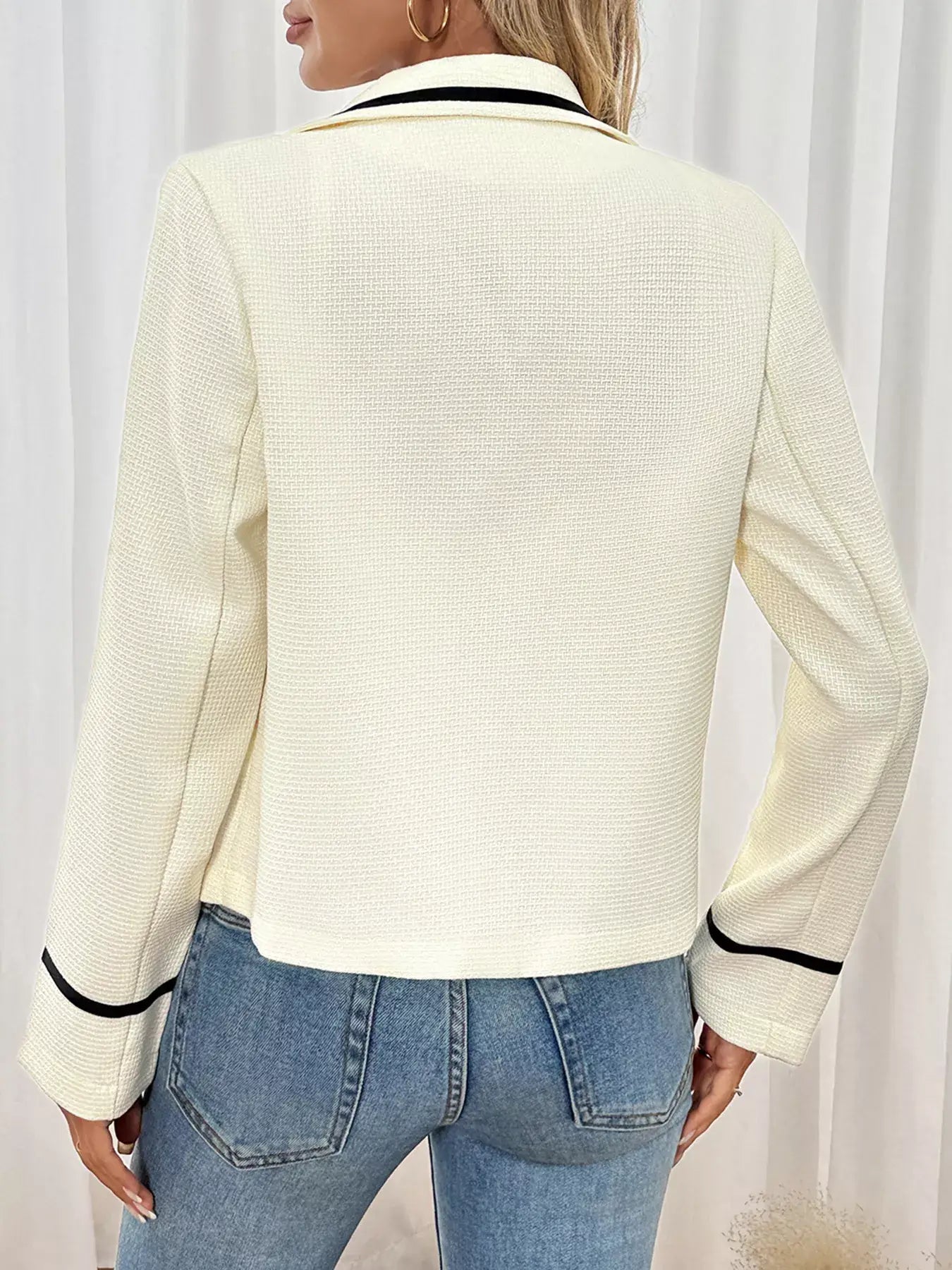 Back view of a woman wearing the Contrast Trim Button-Up Blazer in cream with black trim details.