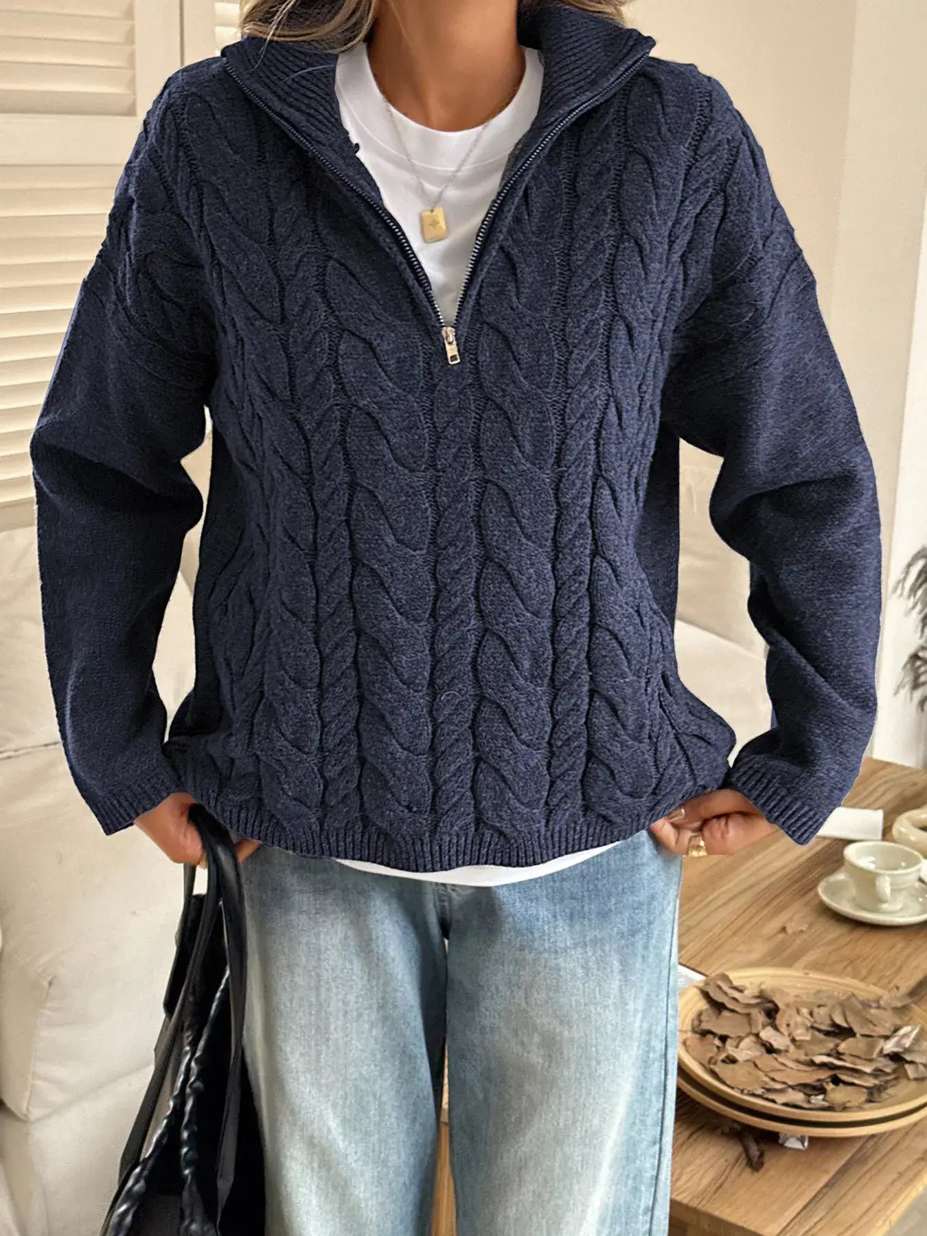 Woman wearing a zip collar cable-knit sweater in navy with a chunky knit design and zip-up collar for warmth.