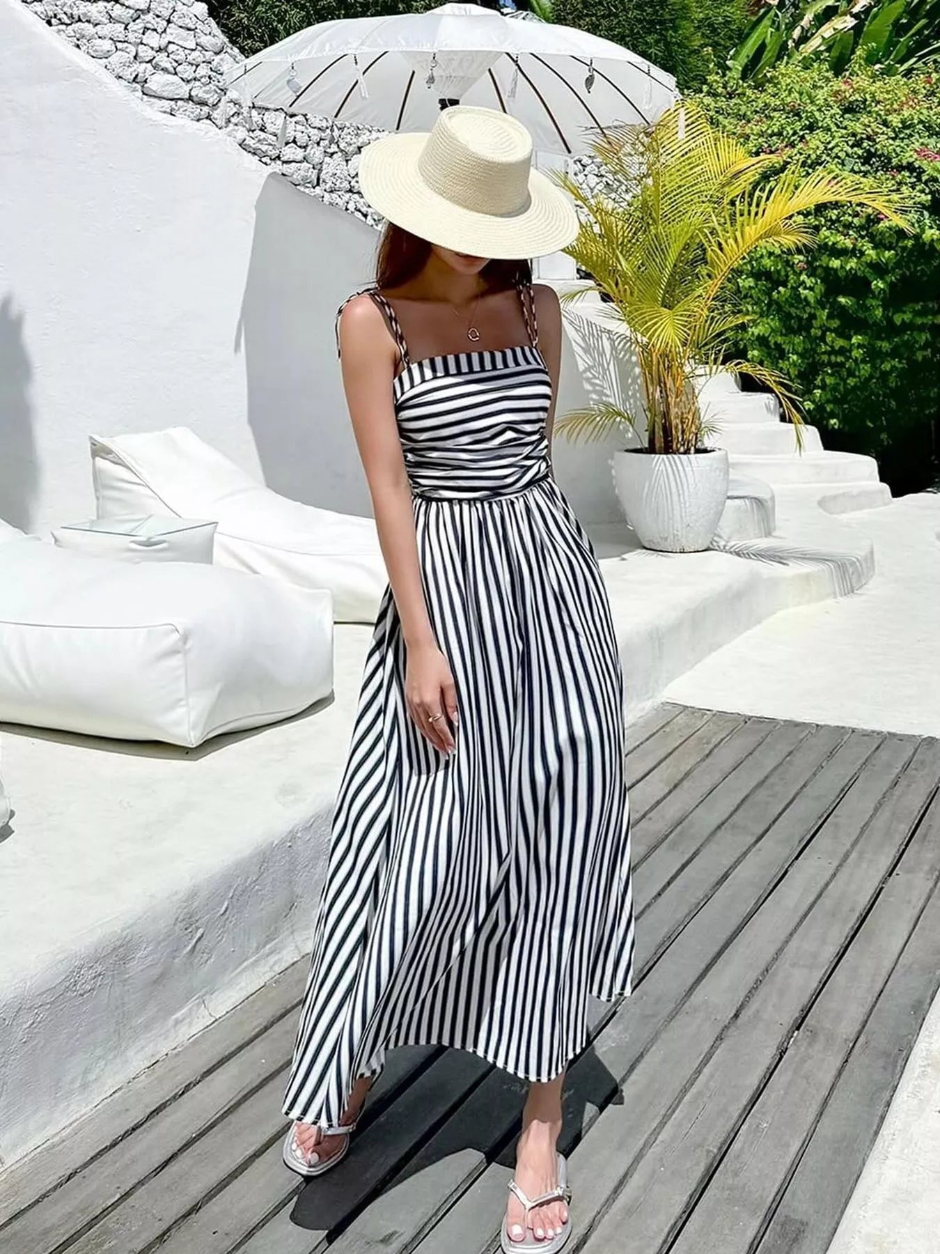 Striped Spaghetti Strap Casual Maxi Dress for Summer Wear modeled outdoors with a sunhat and tropical background.