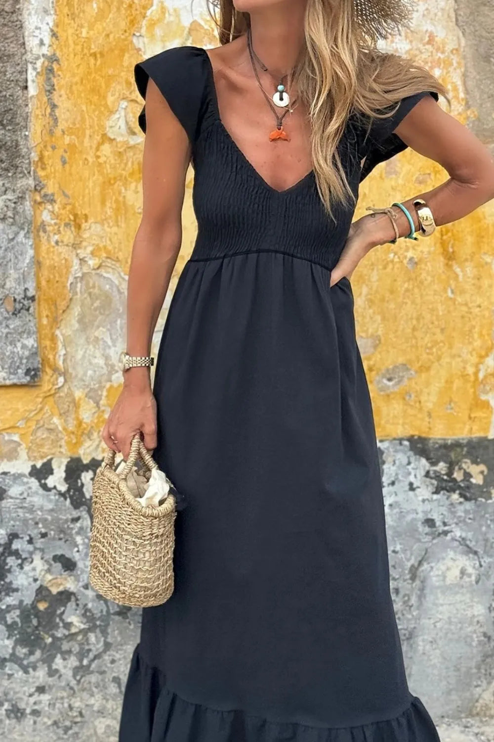 V Neck Ruffled Cap Sleeve Smocked Maxi Dress for Summer Style worn by a woman with a straw bag against a textured wall.