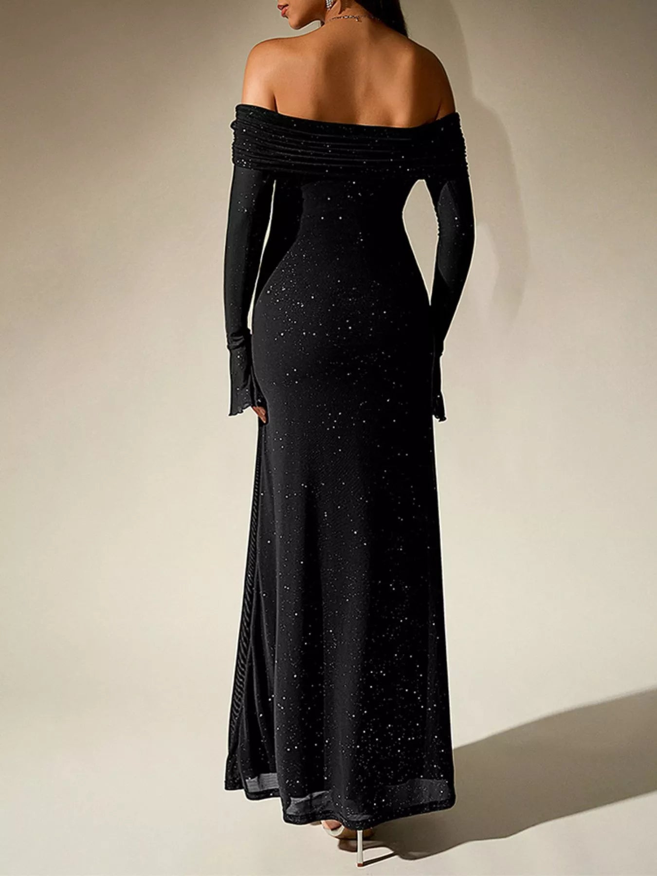 Back view of a woman wearing a Glitter Off-Shoulder Maxi Dress, showcasing its elegant design and shimmering details.