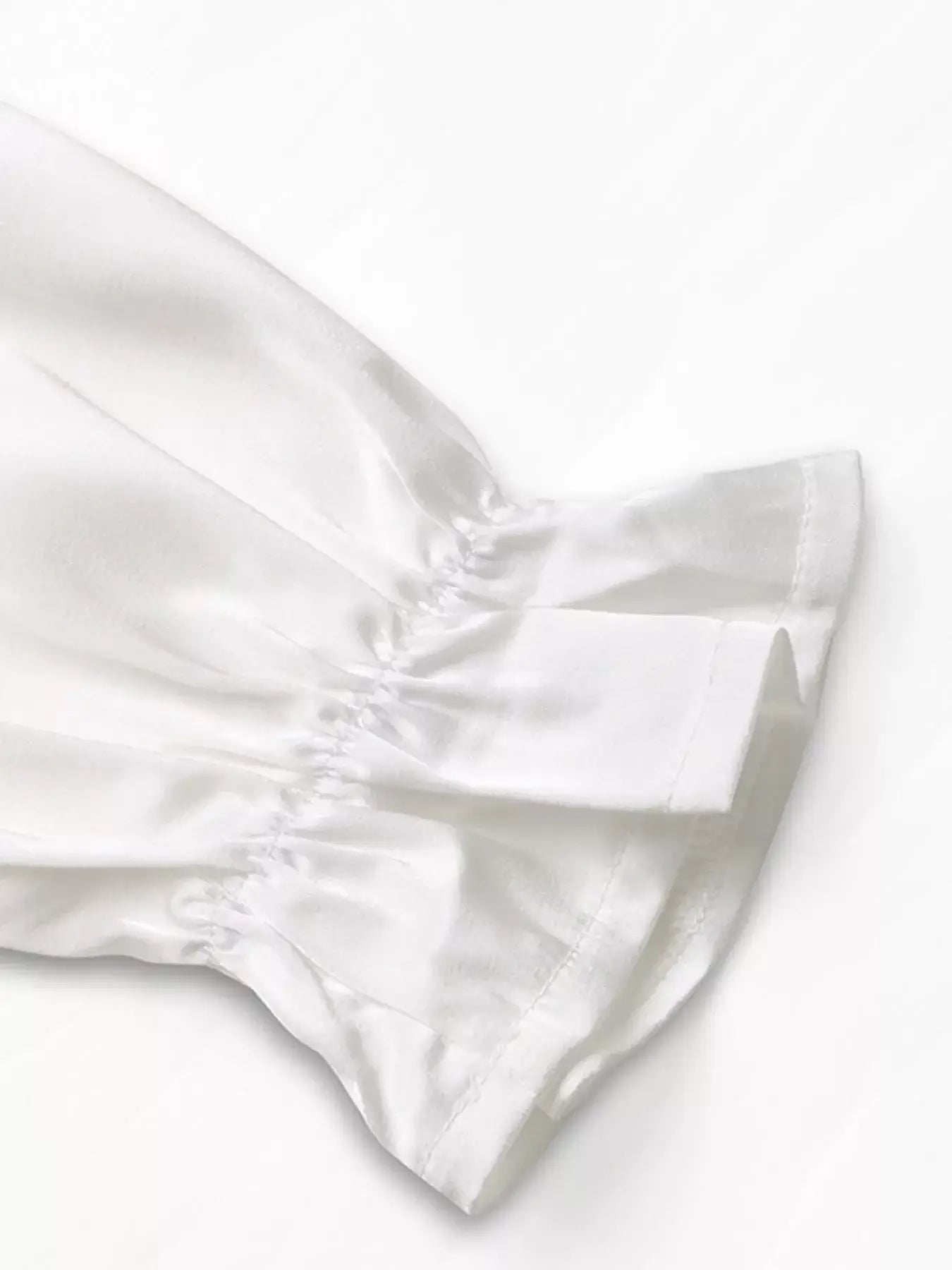 Close-up of the ruffled sleeve detail of the Ruffled Cold Shoulder Flounce Sleeve Blouse in elegant white fabric.