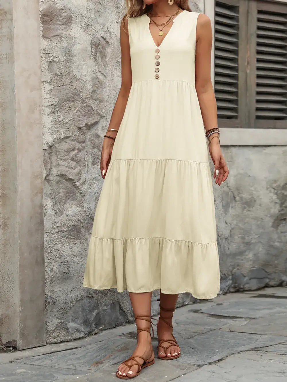 Model wearing Ivy Lane Decorative Button Notched Sleeveless Dress in light color with decorative buttons and flared skirt.