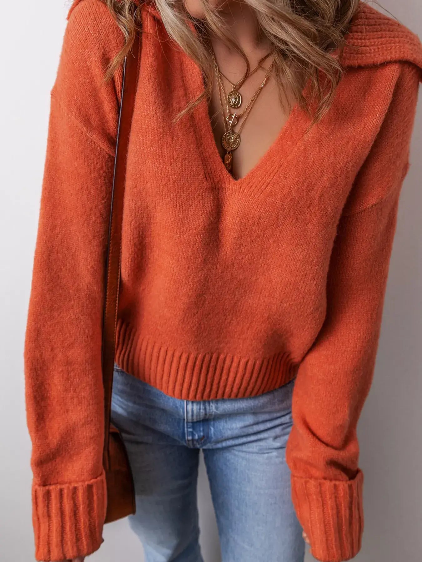 Model wearing a collared v neck ribbed edge sweater in orange, featuring a flattering V-cut and ribbed hem.