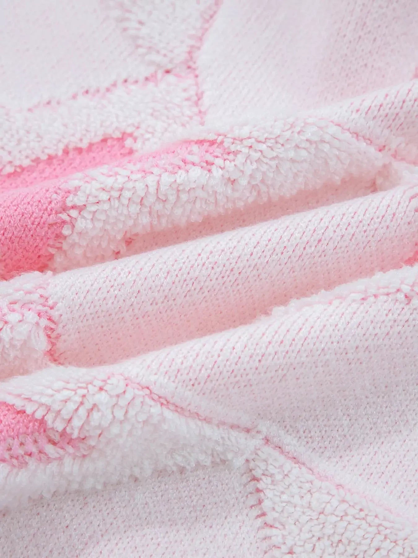 Close-up of the fabric texture from the oversized star pattern ribbed edge drop shoulder sweater in pink.